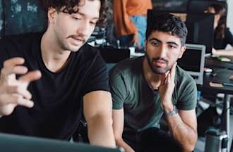 [Featured image] Two systems engineers collaborate in front of a laptop computer.