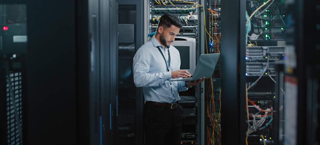 [Featured Image} A person working in cybersecurity looks at a laptop with a key AI application. 