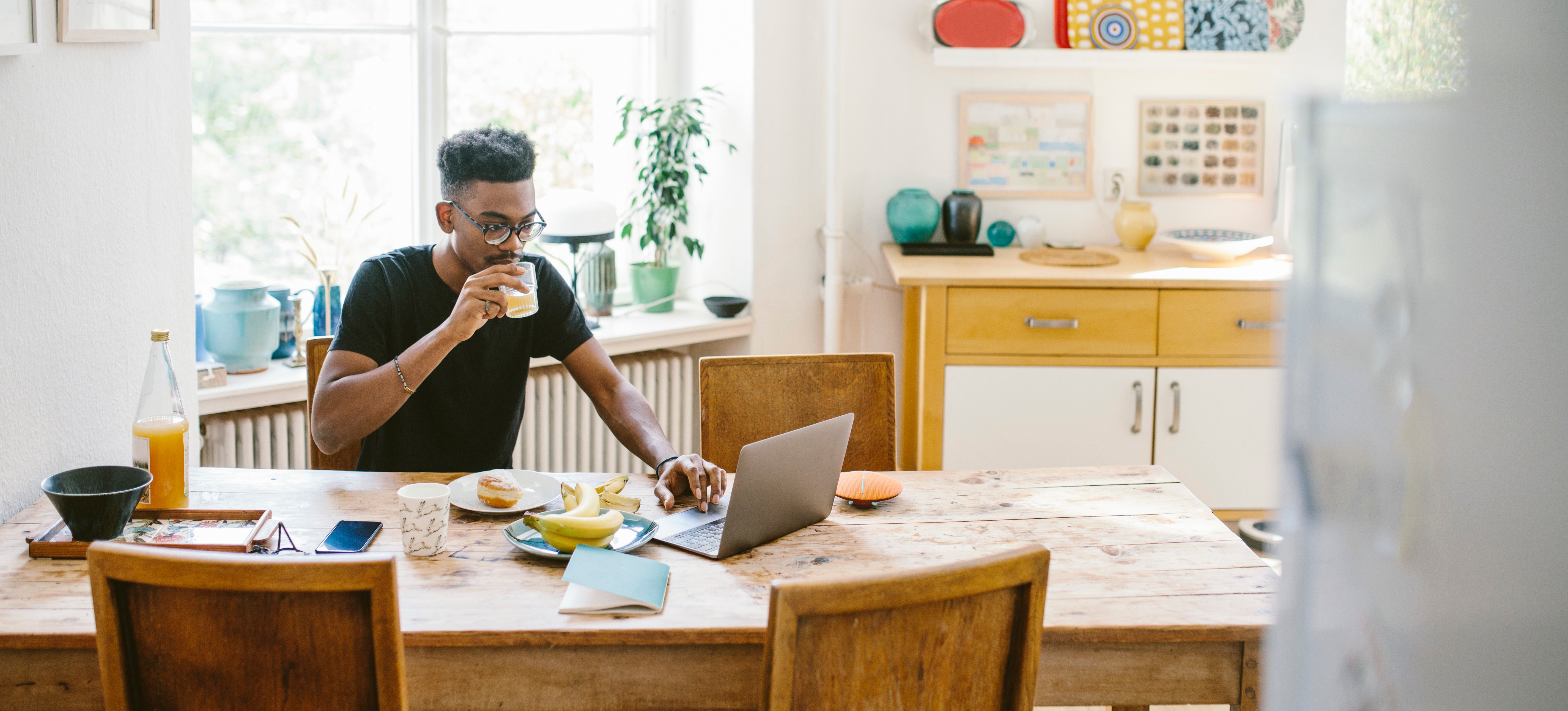 [Featured Image] Person searches for cloud certifications on his laptop in his dining room while eating lunch.