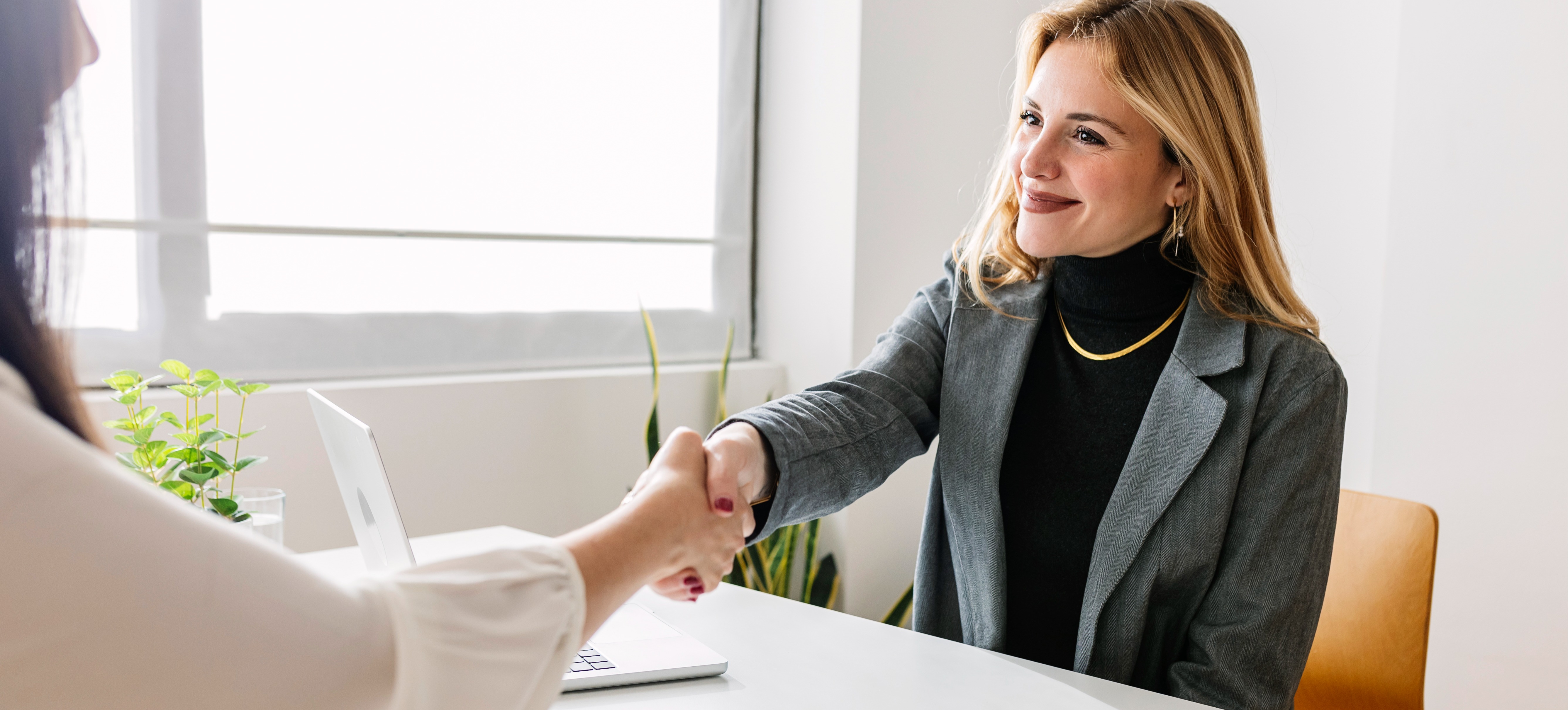 [Featured image] Smiling HR manager shaking hands with a candidate at an interview to get a job