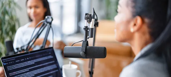 [Featured Image] A podcast creator is recording with a guest and discussing a topic they researched using AI without plagiarizing.
