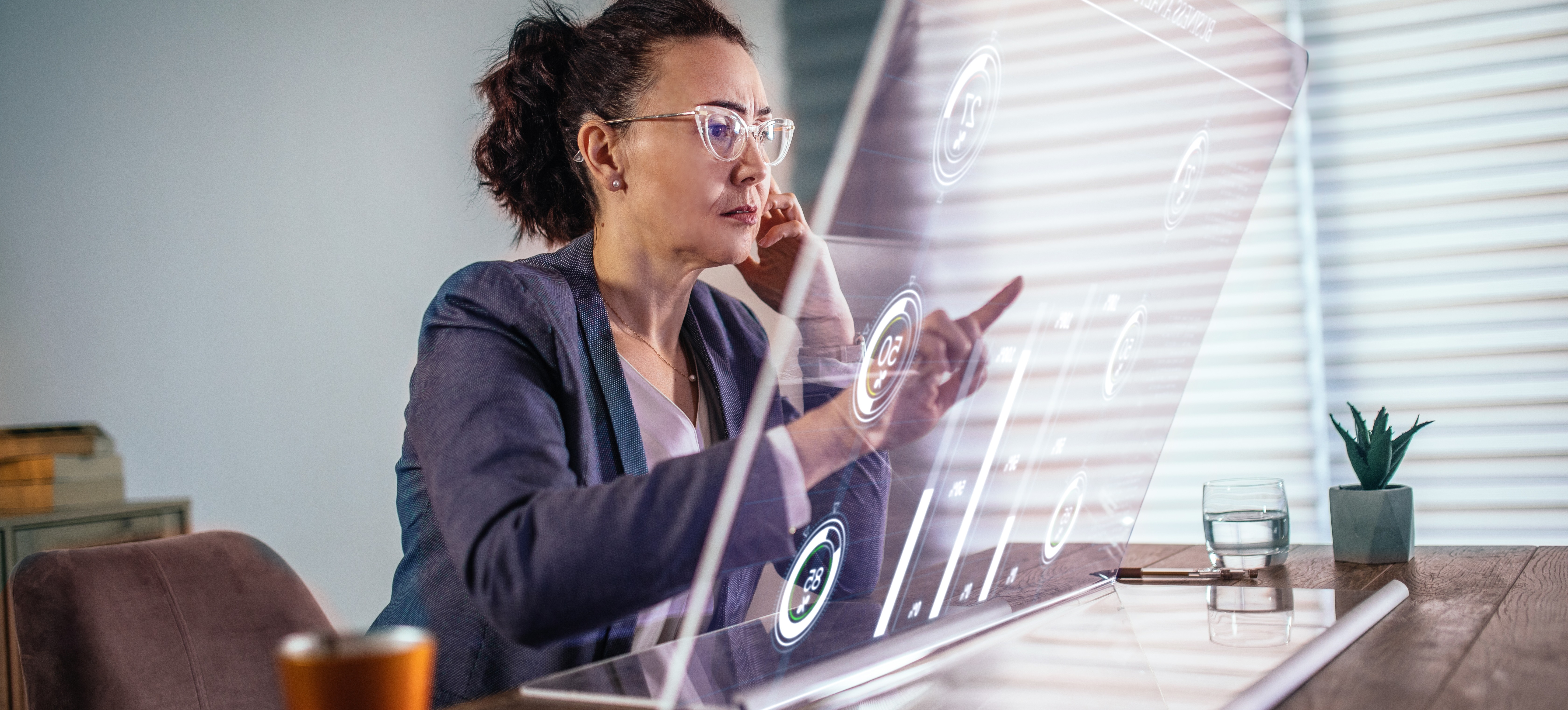 [Featured Image] Businessperson working on futuristic hologram device in an office while contemplating whether AI could replace CEOs.

