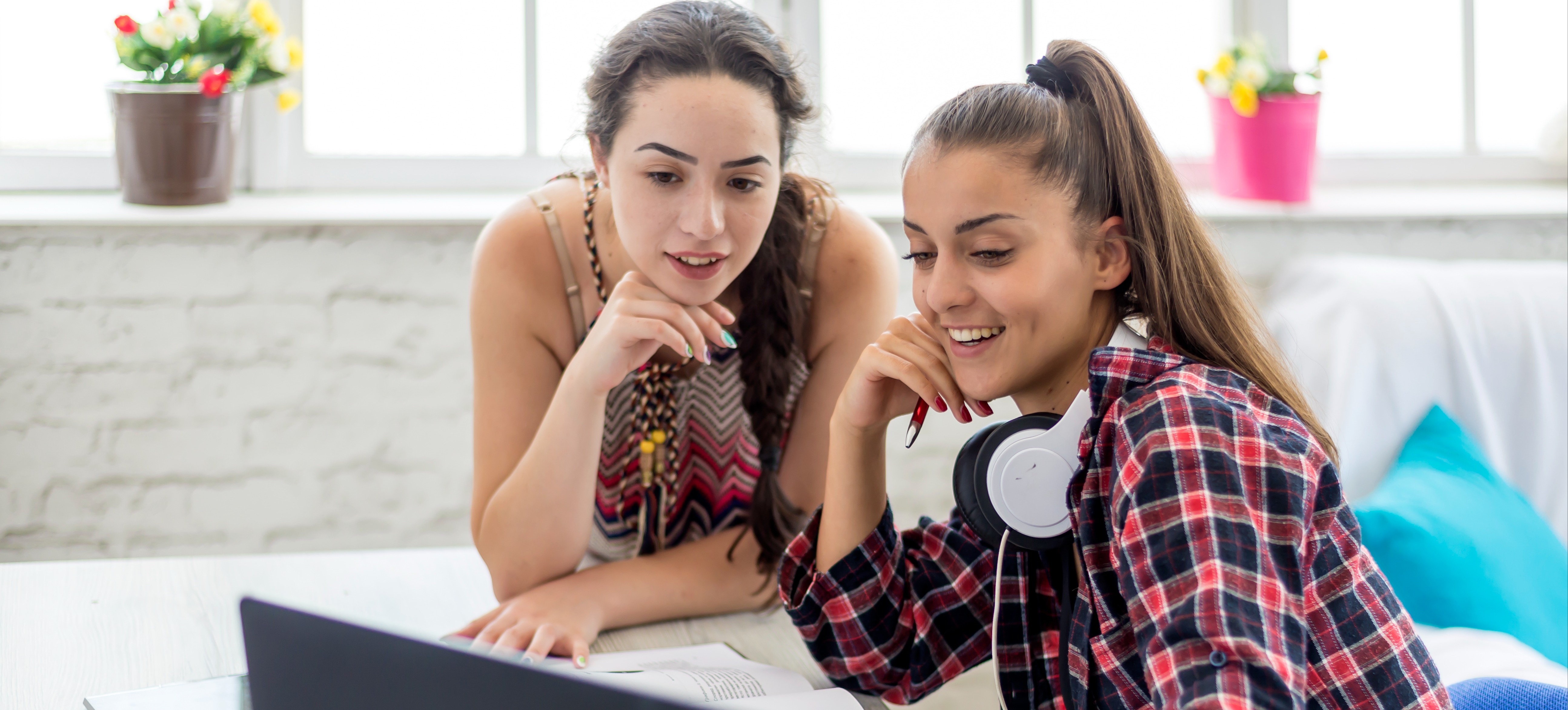 [Featured Image] Two members of a marketing team look at a laptop and discuss what their next marketing project will be.  