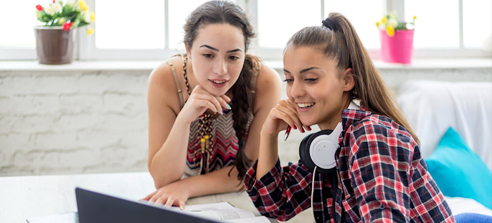 [Featured Image] Two members of a marketing team look at a laptop and discuss what their next marketing project will be.  