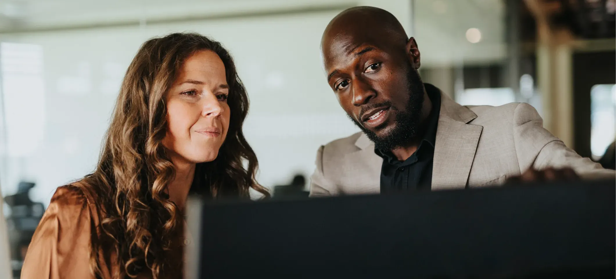 [Featured Image] Two colleagues collaborate on a vibe coding project, reviewing the initial code together on a computer before beginning to refine the results. 
