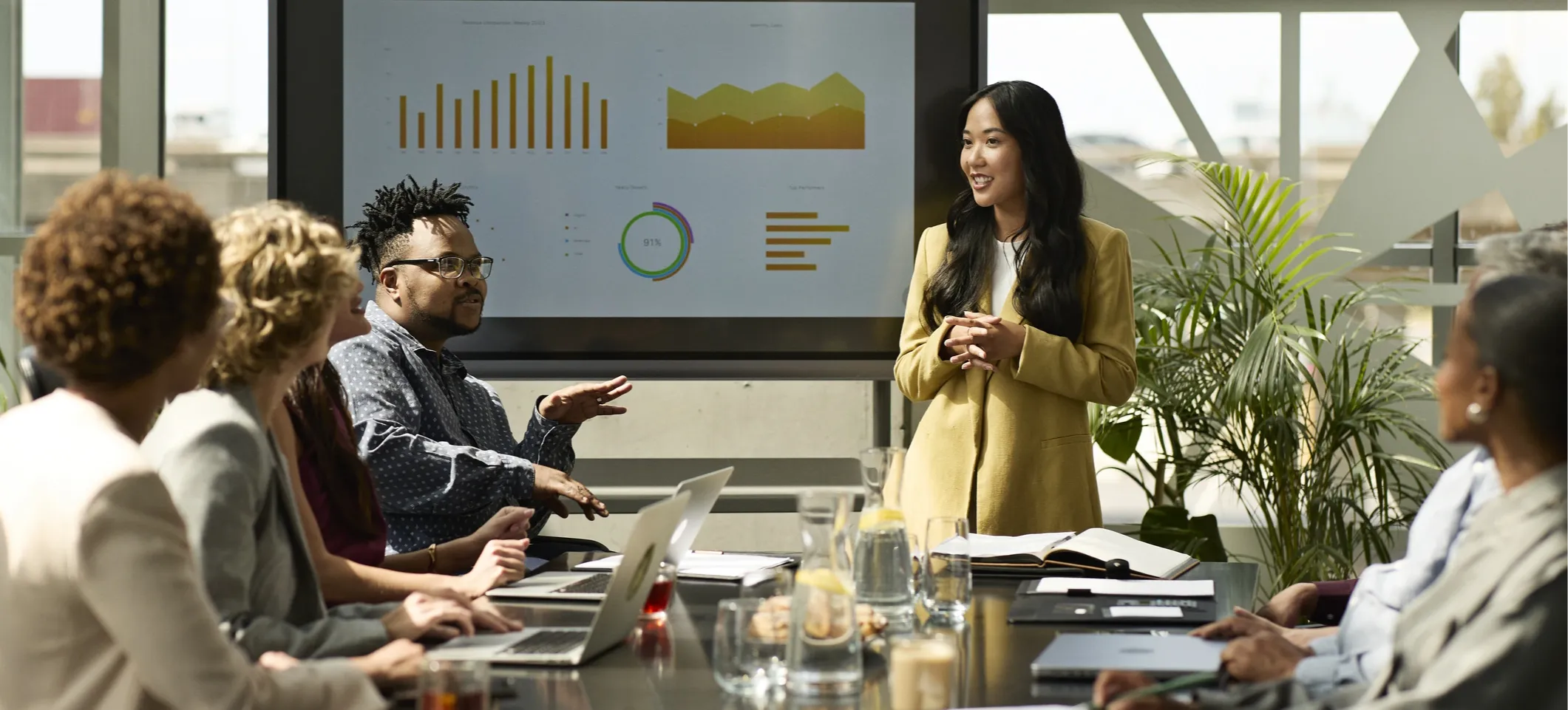 [Featured Image] An IT business analyst stands in front of a data chart in a boardroom and discusses decisions with their team.