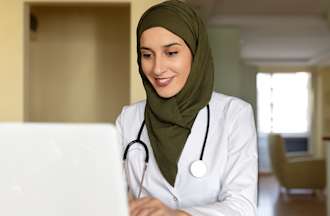 [Featured Image] A nurse works on a laptop.