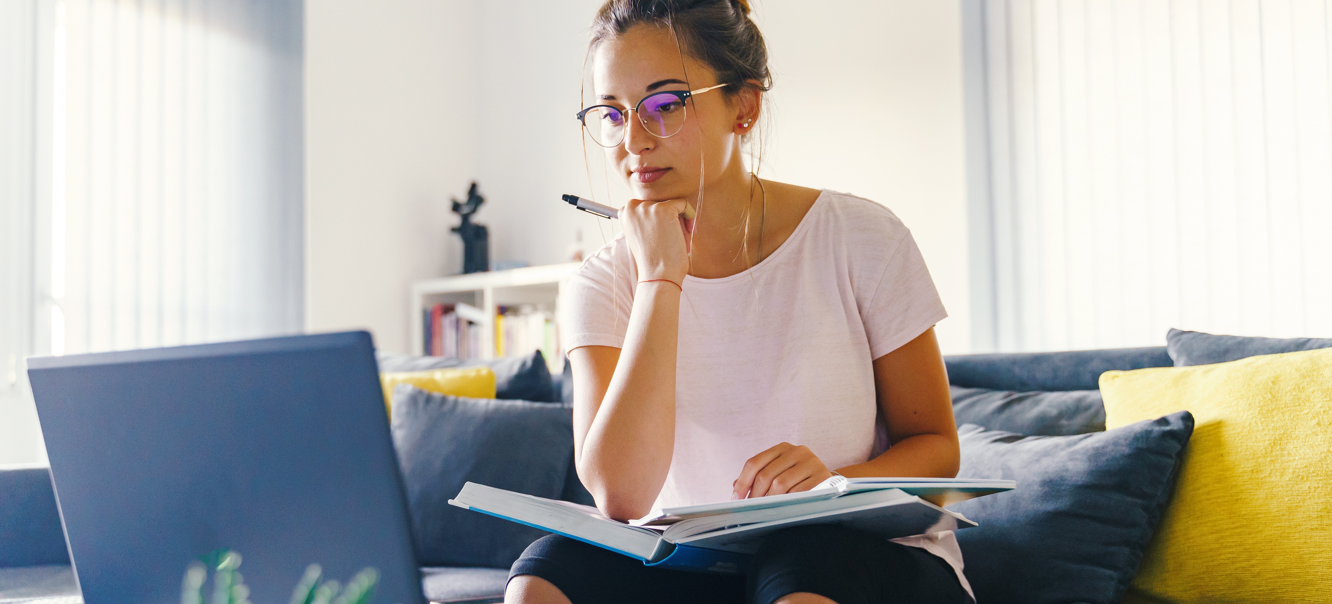 [Featured image] An aspiring college student works on their college essay with a notebook and laptop.