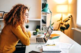 A young prospective female college student looks at a laptop in her home office to determine if she needs a degree to be an accountant.