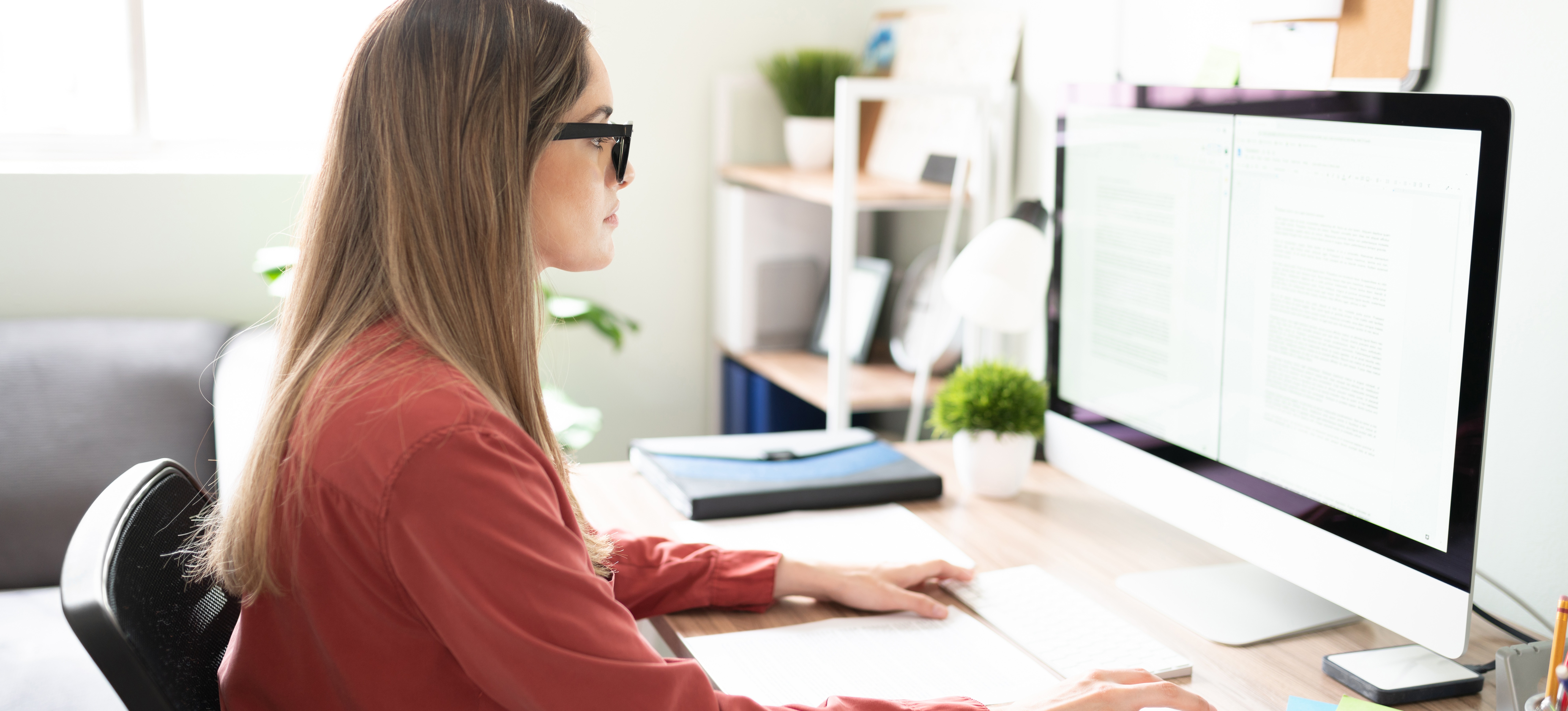 [Featured Image] A person sits at a computer in a sunny home office and uses Keras and Pytorch for a machine learning project.