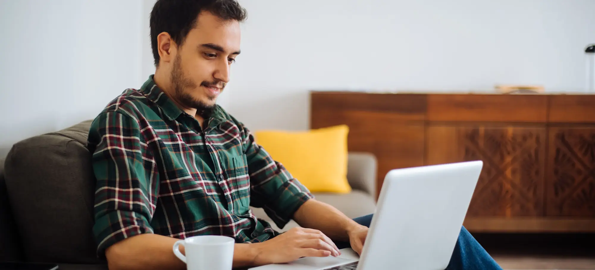 [Featured image] A person in a green plaid button-down shirt sits in a chair and searches for IT jobs on a laptop.