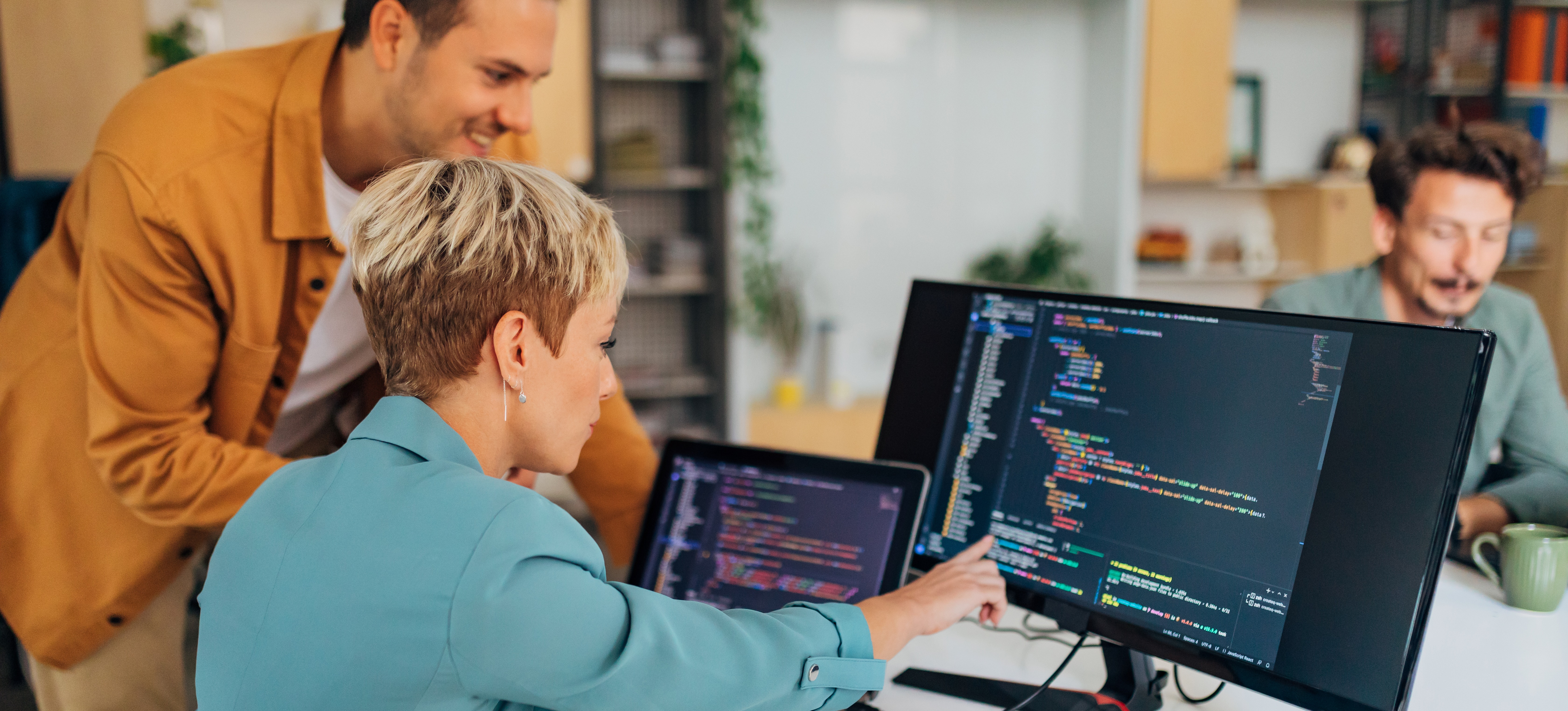 [Featured Image] Software developers in an office performing code completion on a computer screen.
