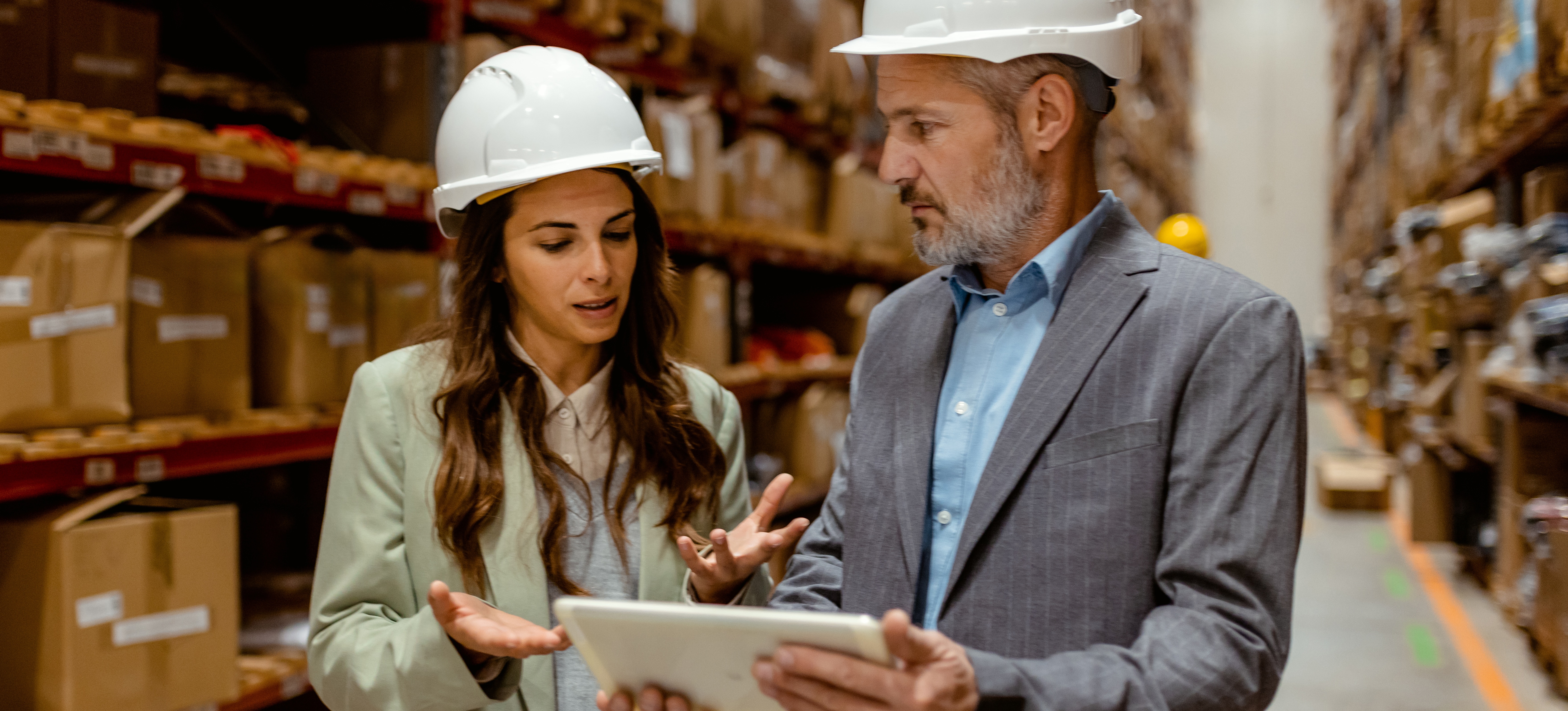 [Featured Image] A risk manager is in a warehouse helping a team member get their risk management certification.

