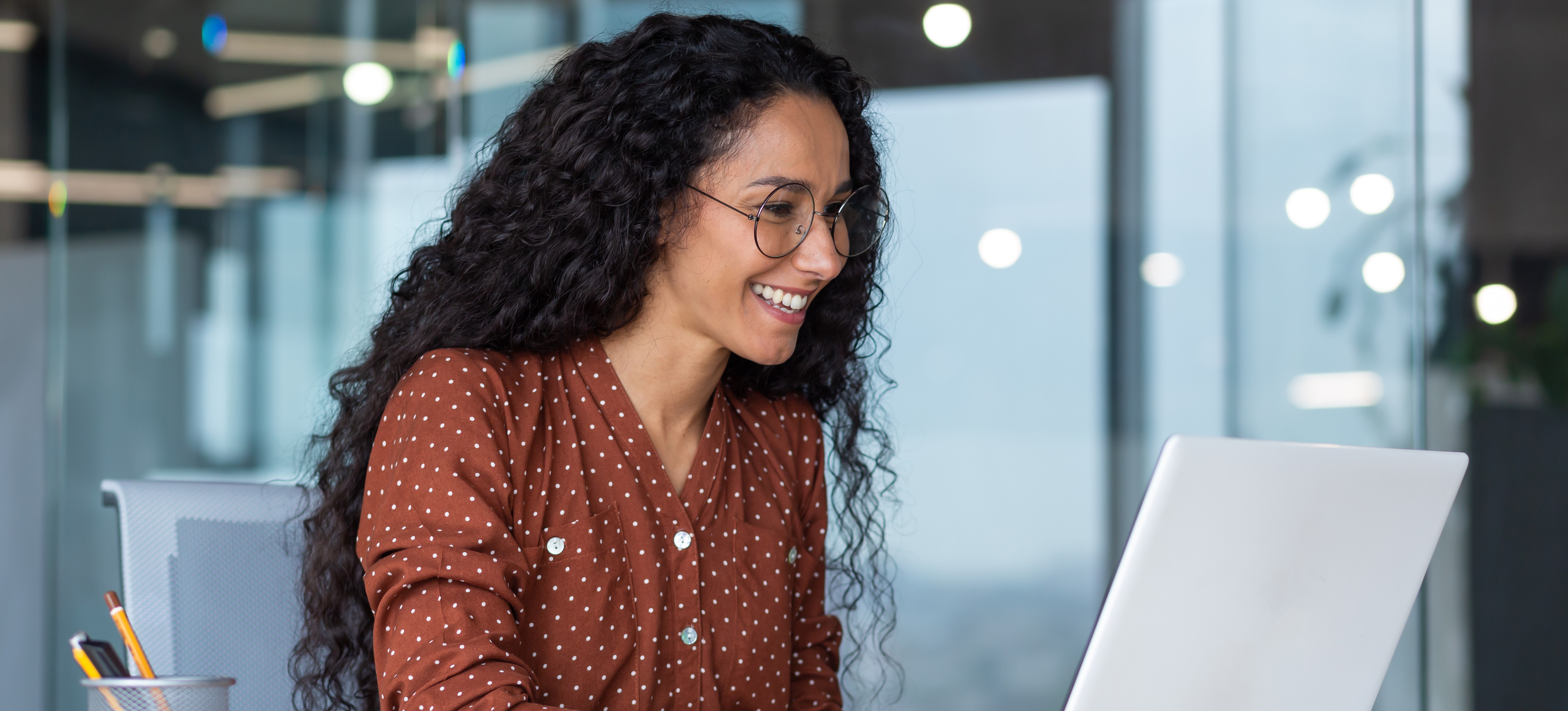 [Featured Image] A person with long black hair works on their laptop in an office and navigates ChatGPT using OpenAI temperature.
