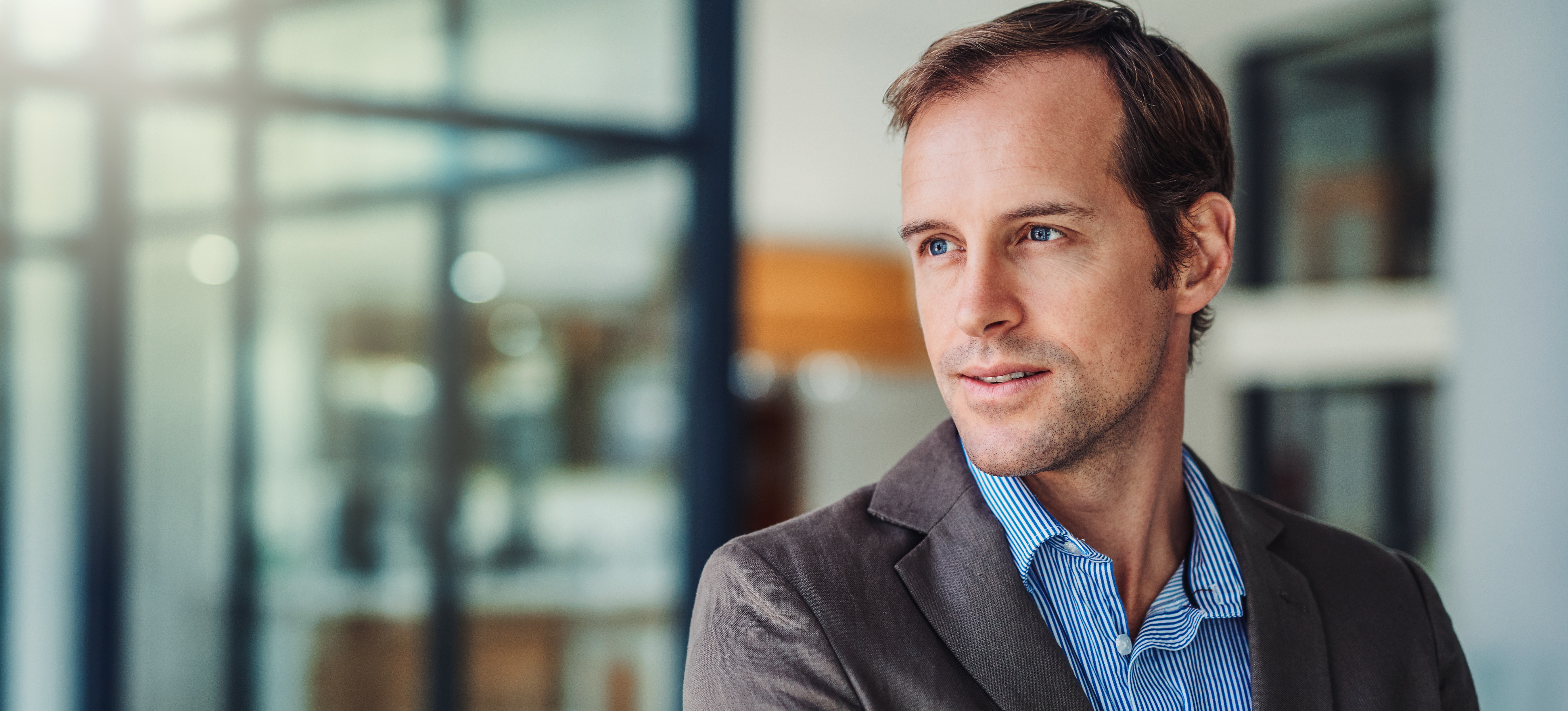 [Featured image] A business employee stands in an office and looks in the distance as they consider if getting an MBA is worth it.