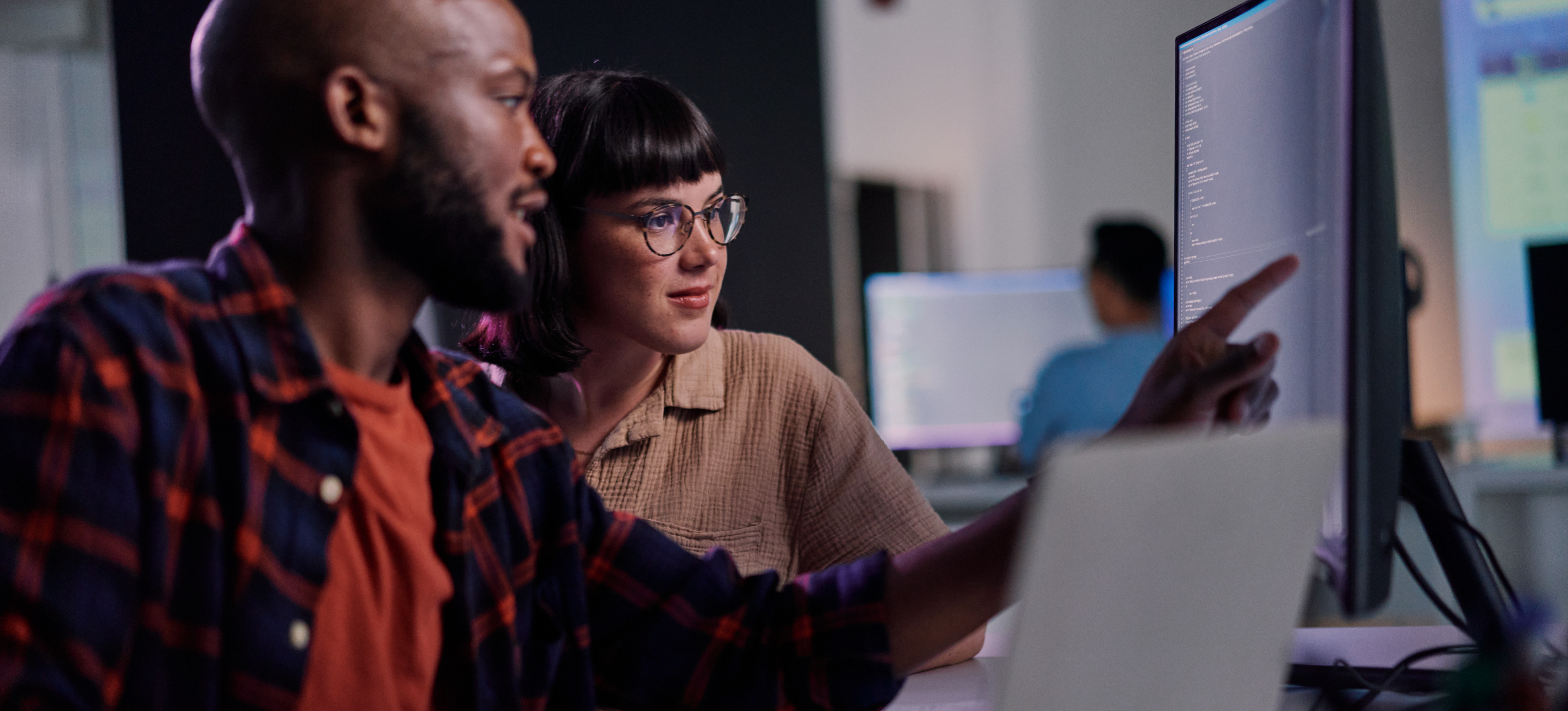 [Featured Image] AWS specialists in a workplace, looking at code on a computer screen and discussing the differences between AWS Certified AI Practitioner and AWS Certified Cloud Practitioner.