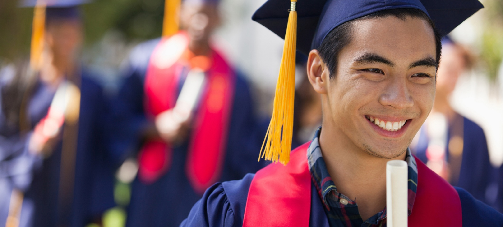 [Featured Image] A graduate stands in their cap and gown, holding a rolled scroll and wondering, “Do jobs ask for proof of a degree?” and if so, how they should provide that proof.