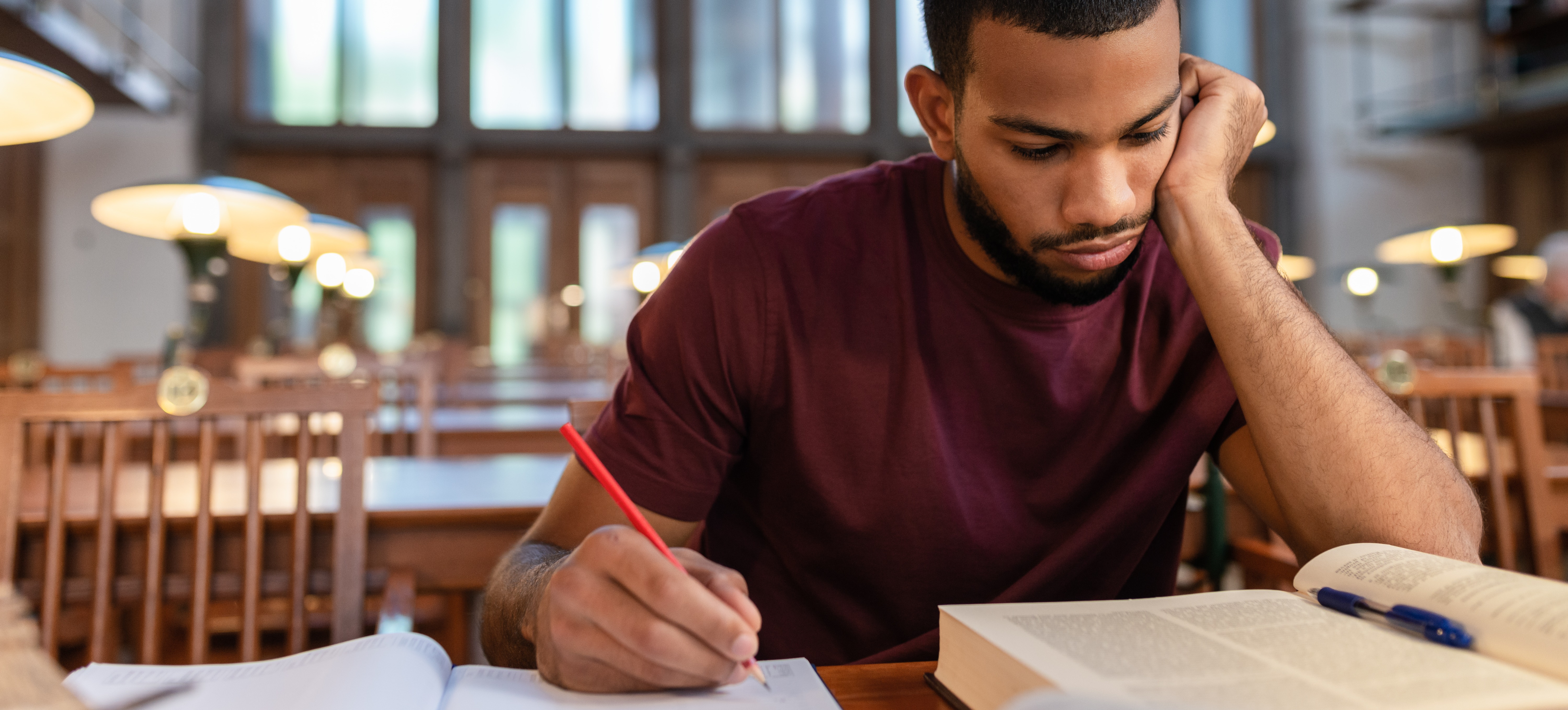 [Featured Image] A college student studies in the library after failing a class in college. 
