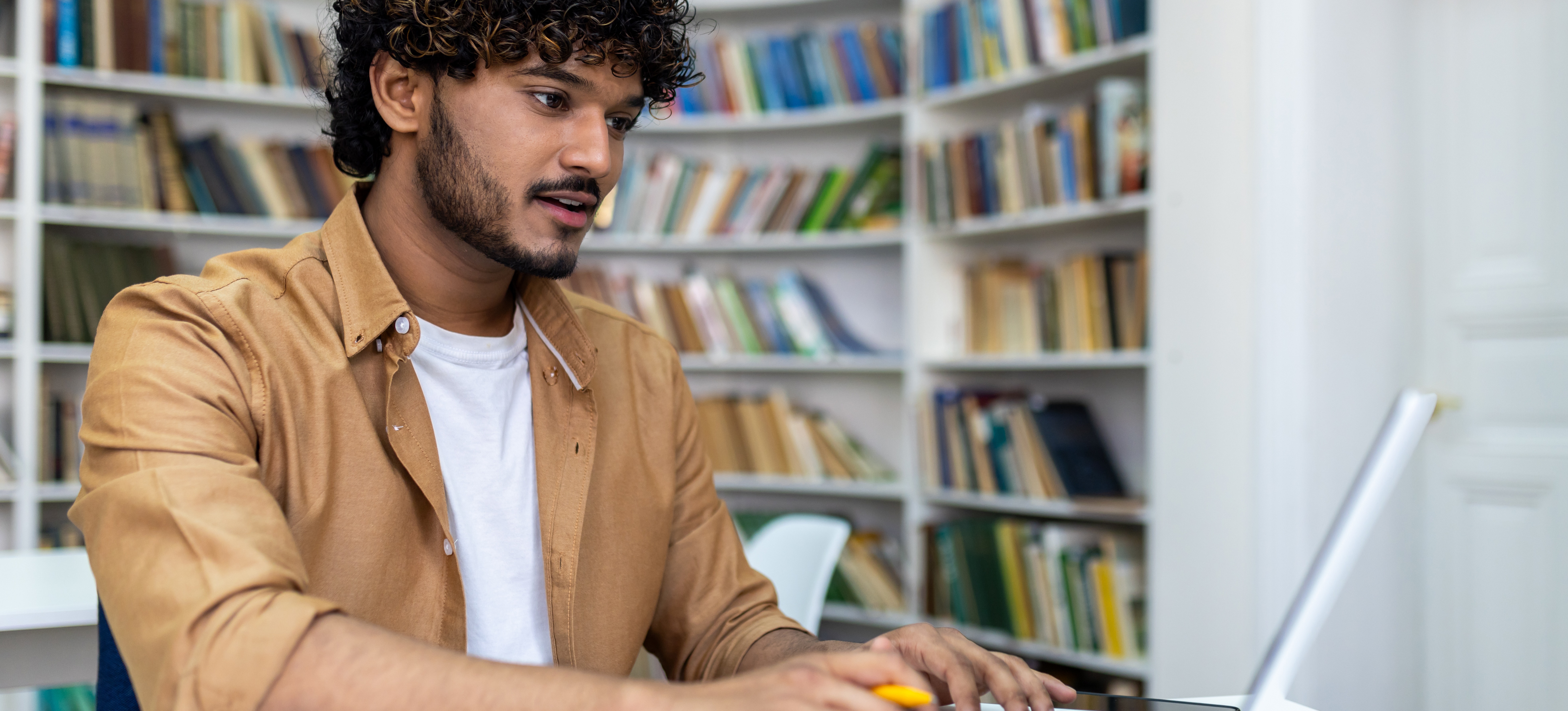 [Featured Image] A young student sits at a laptop and researches whether they can take engineering courses without JEE. 
