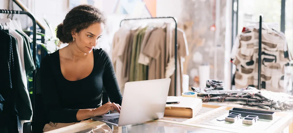 [Featured Image] A dress shop owner learns how to use GIFs in Google Display Ads as they sit a their laptop in their shop.