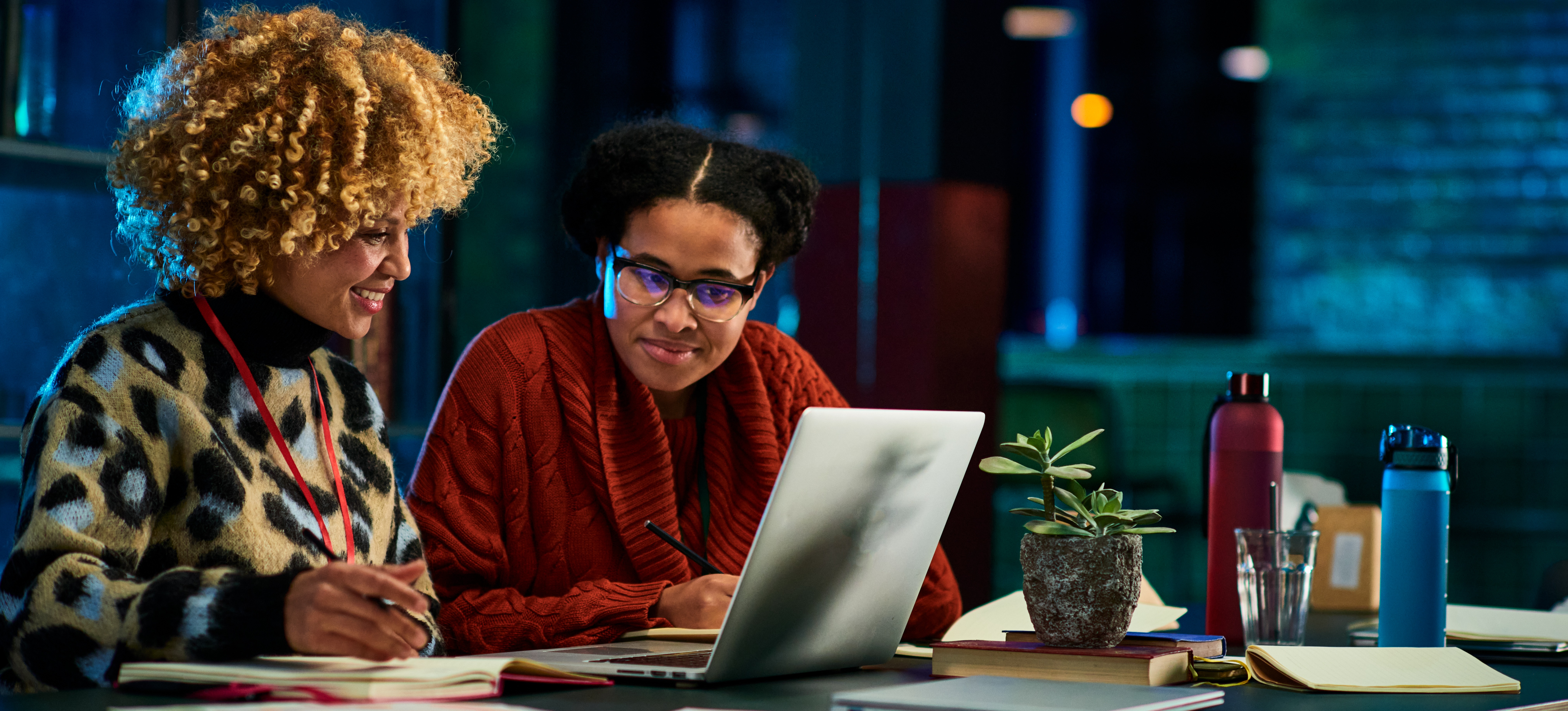 [Feature Image] Two learners study for their Google Cloud certification exams together using practice questions on their shared laptop computer.
