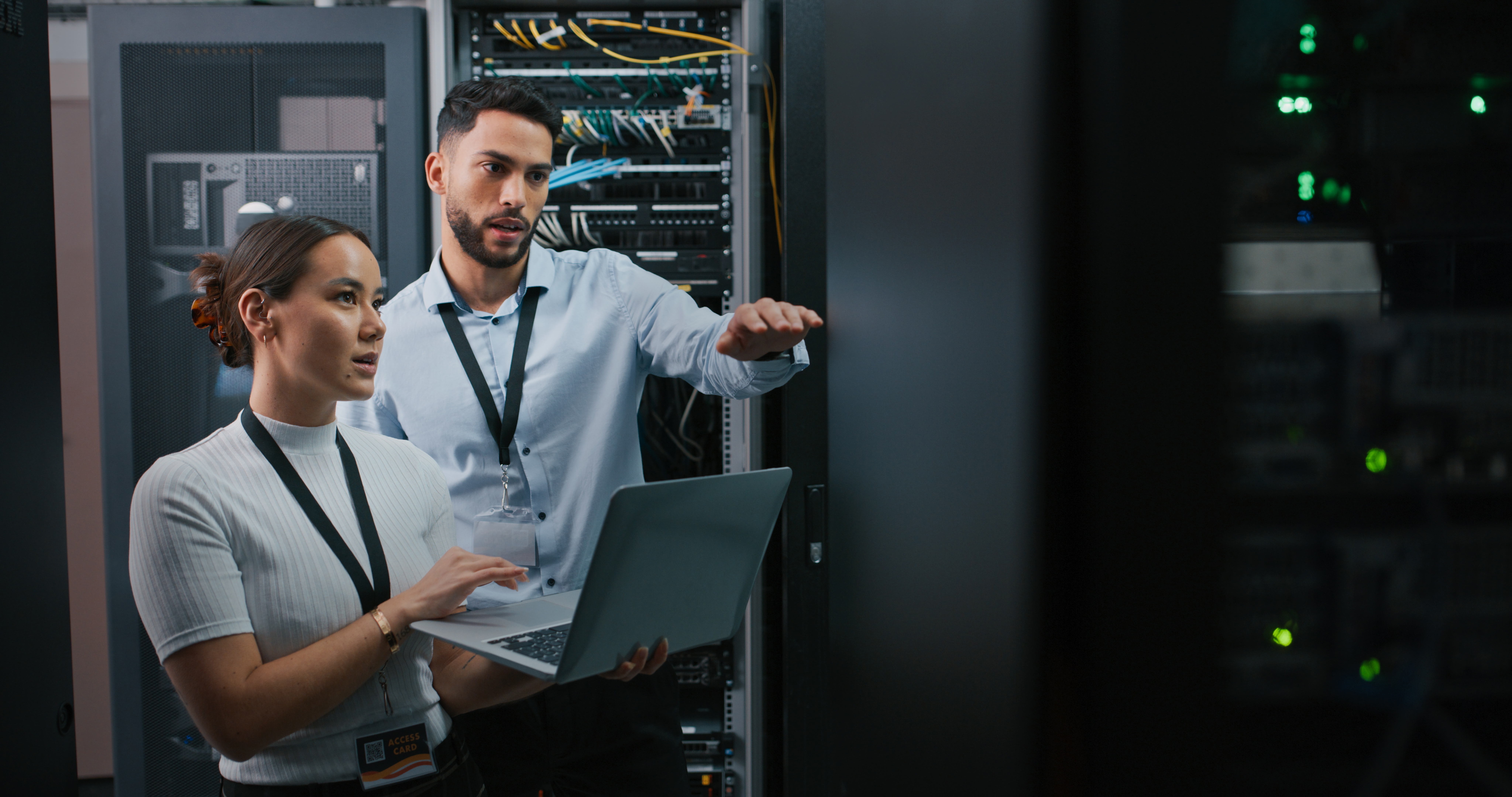 [Featured Image] Two network engineers working together in a server room
