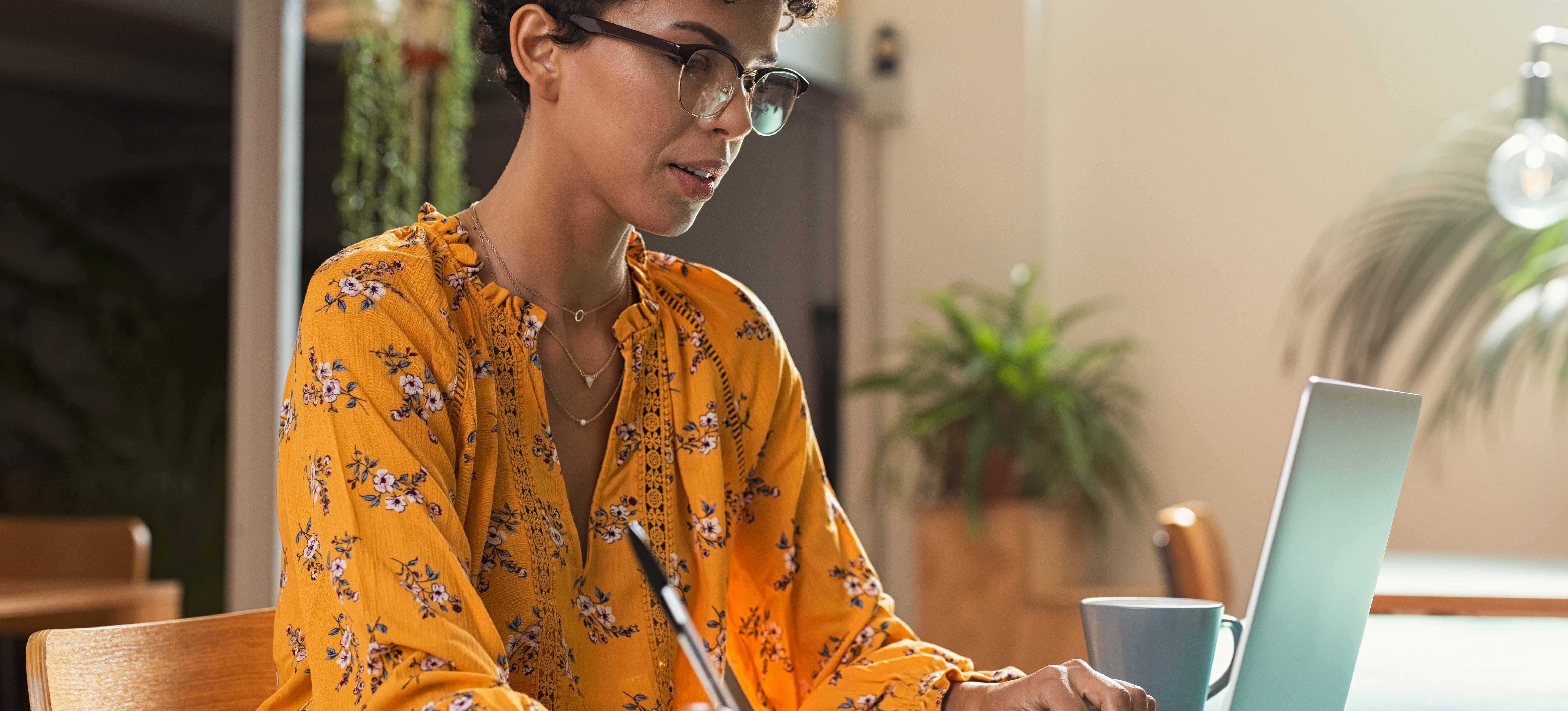 [Featured Image] An MBA student studies on a laptop while taking notes.
