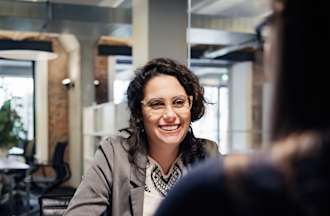 [Featured Image]:  An employee wearing a gray jacket using negotiation skills while talking to a manager.