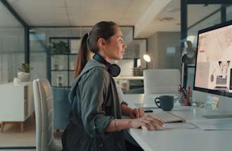 [Featured image] A website designer works on a website mockup on her desktop computer.