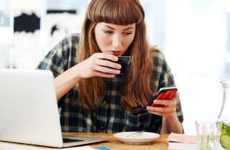 [Featured image] A person browses web pages on their phone and computer while drinking a cup of tea.
