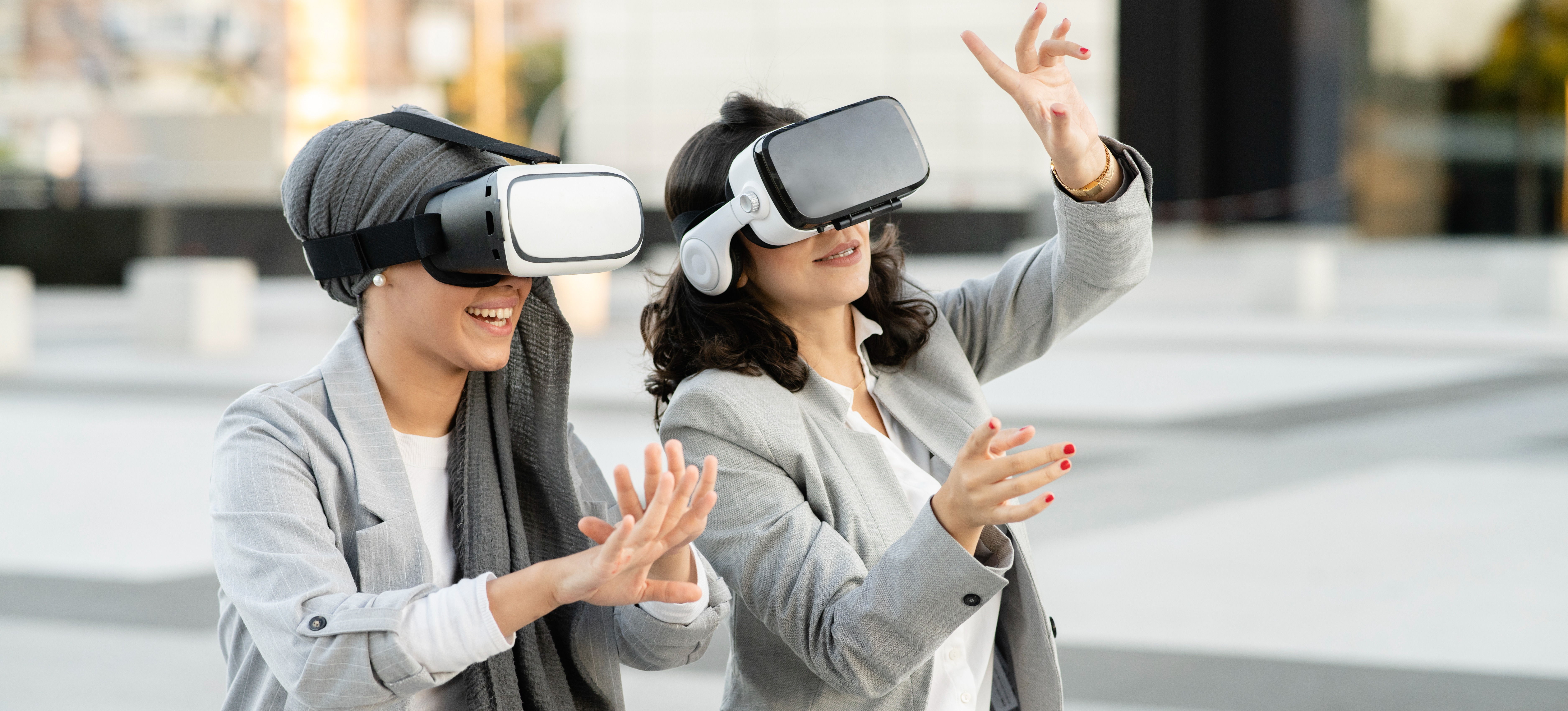 [Featured Image] Two business professionals sit outside and use VR headsets that utilize VR eye tracking. 