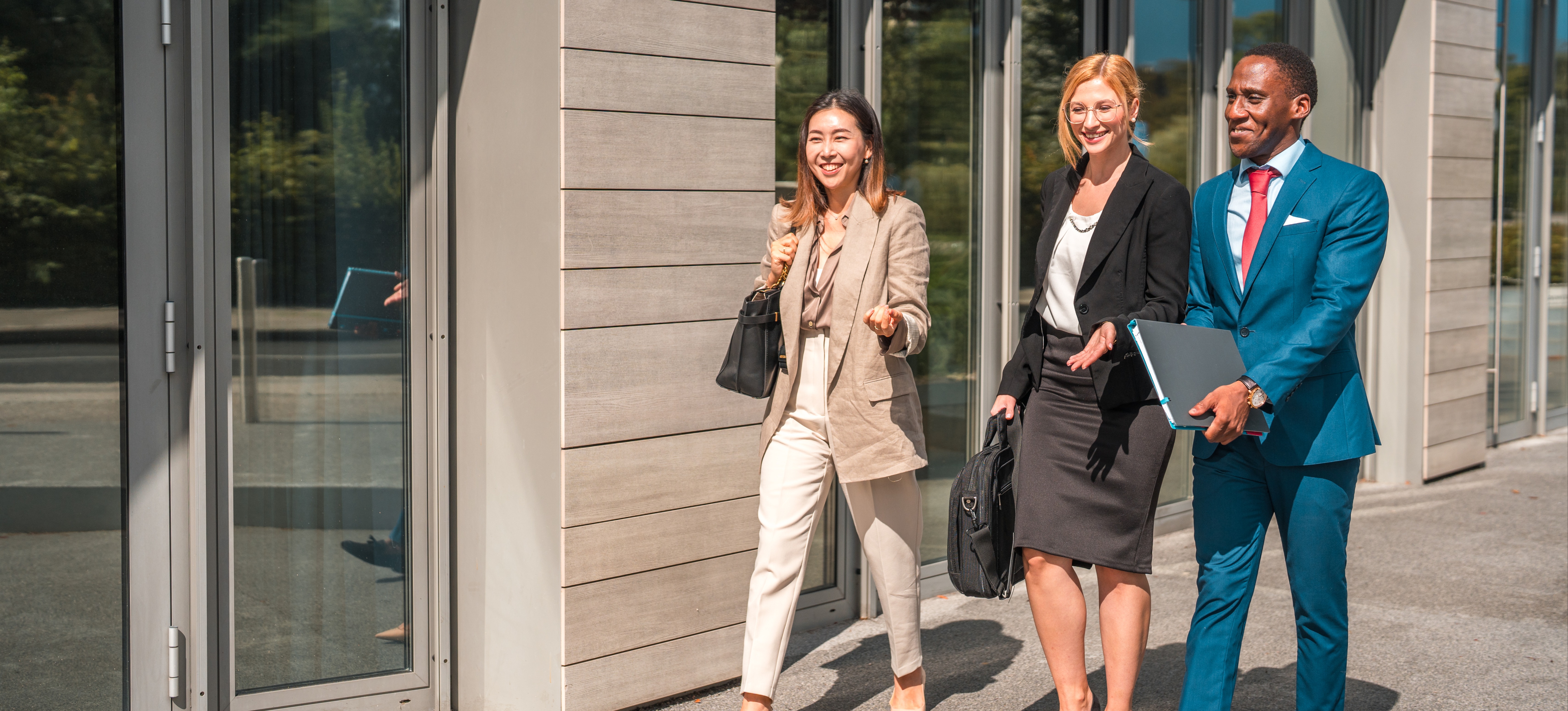 [Featured Image] A group of three employees carrying folders and briefcases walk outside toward a building where they perform their cybersecurity jobs in Las Vegas.
