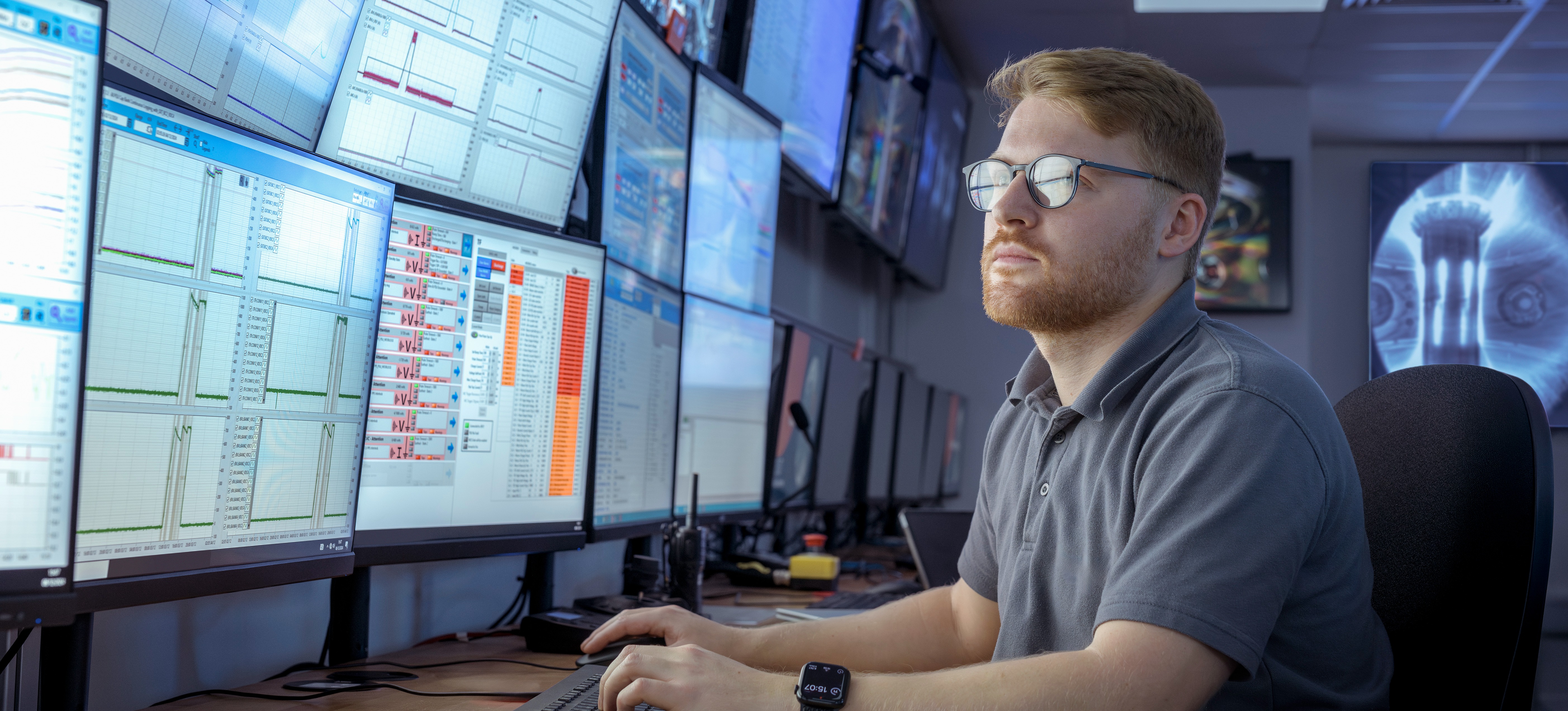 [Featured Image] A scientist is using applied statistics to understand data showing on screens in a control room.
