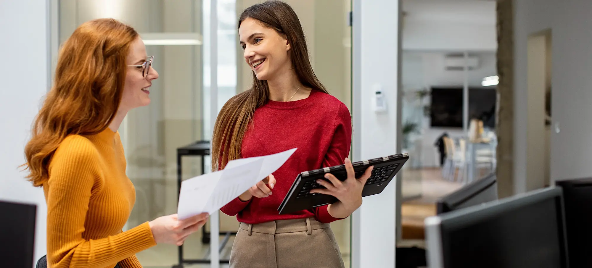 [Featured Image] A smiling HR professional holding a laptop uses skills learned from their CCP certification as they speaks with another colleague.
