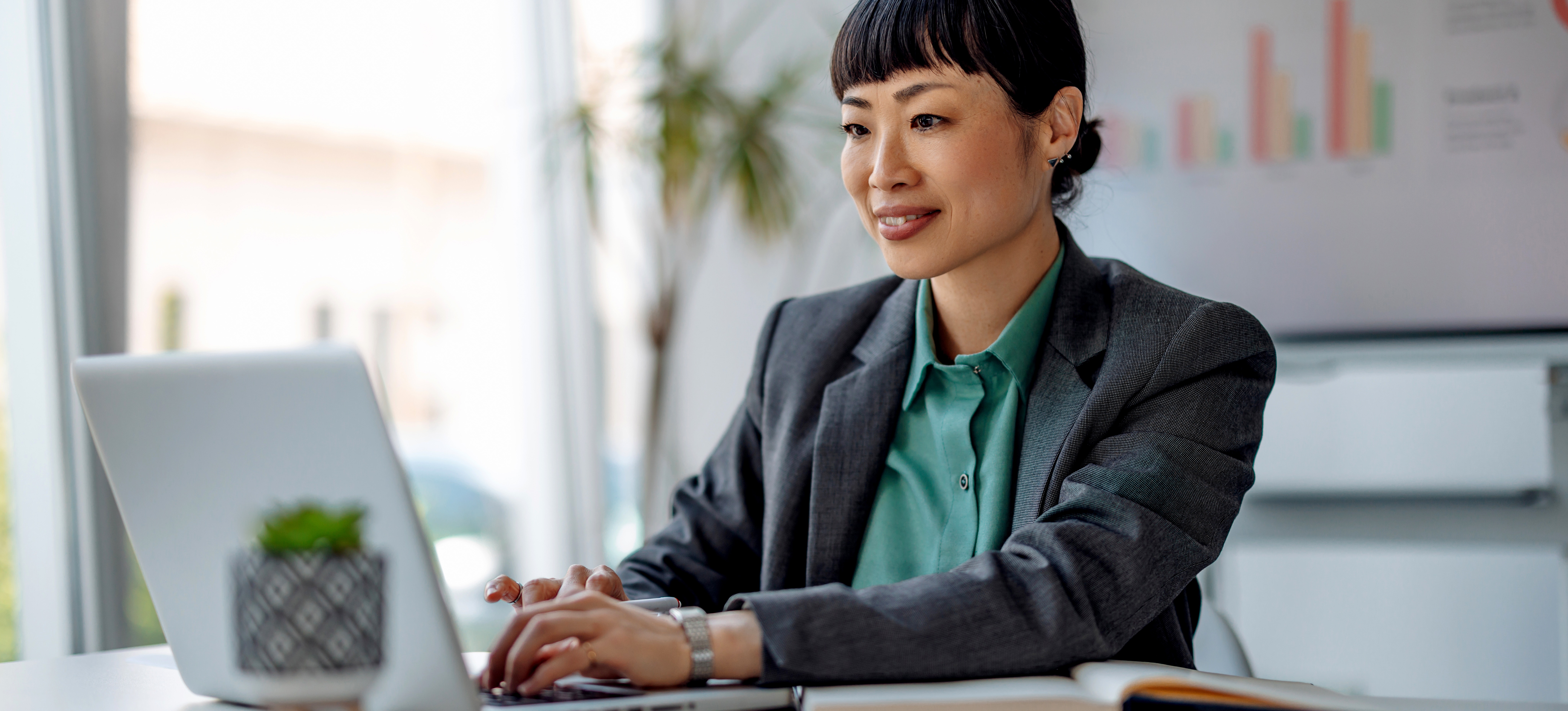 [Featured image] A data analyst wearing a business suit works with predictive analytics on their laptop in a sunny office setting.

