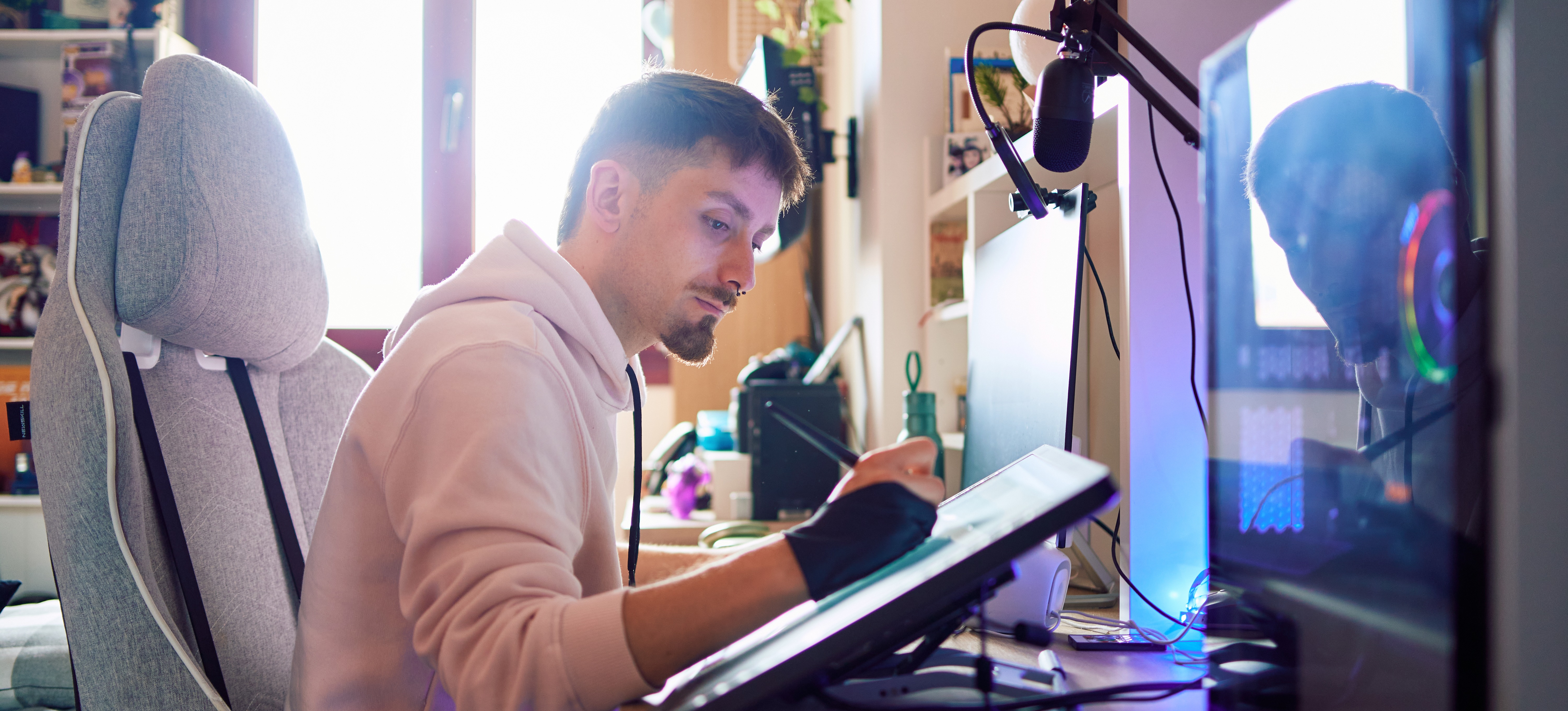 [Featured Image] A graphic designer sits at his desk in his home office and works on a project using digital tools.
