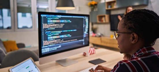 [Imagen destacada]:  QA Tester, trabajando en un ordenador de sobremesa, identificando y analizando problemas durante el proceso de depuración del software. 