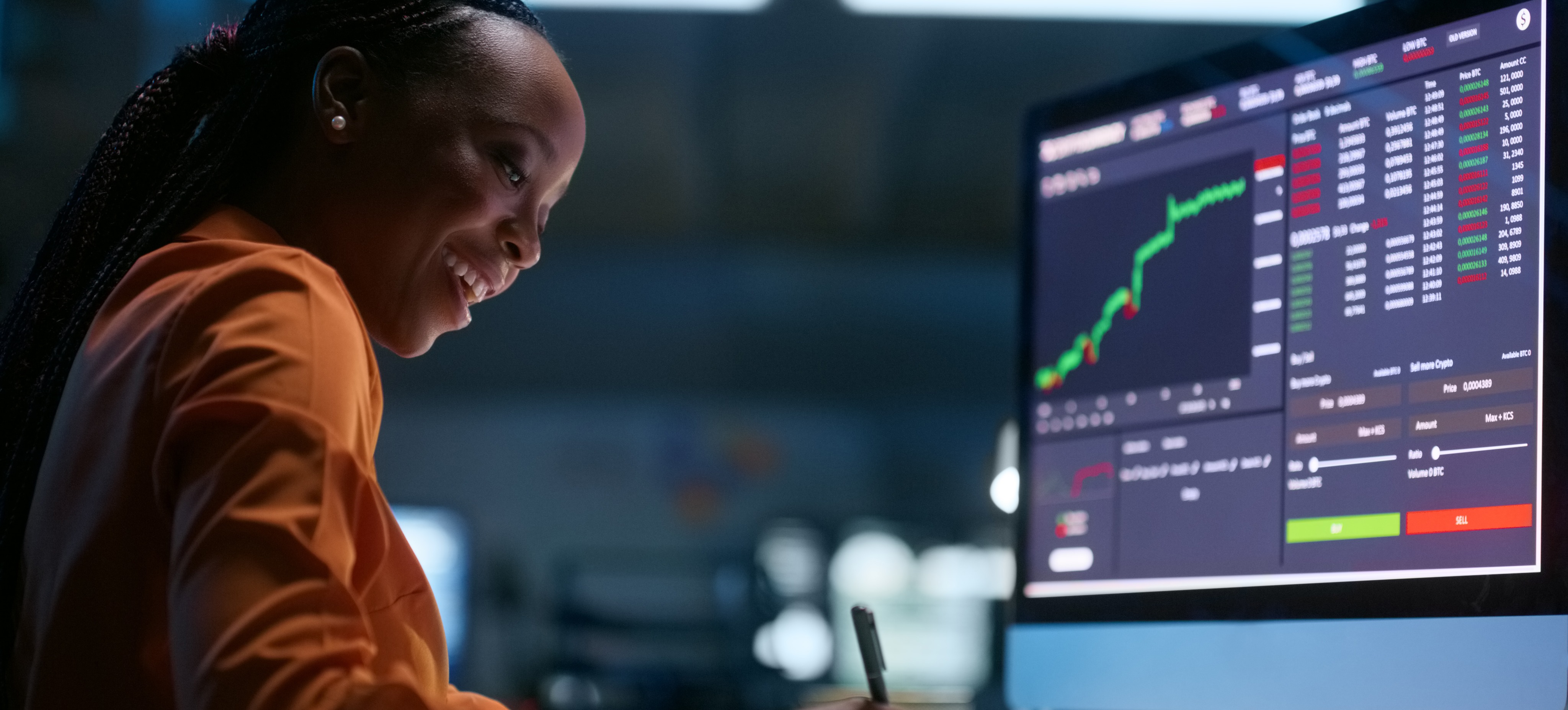 [Featured Image] A smiling data scientist analyzes data featuring outliers at their desk and has graphs displayed on their computer monitors.