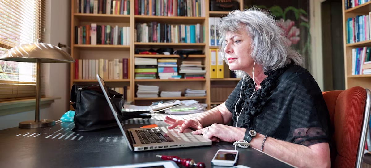 [Featured image] A professor writes a letter of recommendation on their laptop in an office filled with bookshelves.