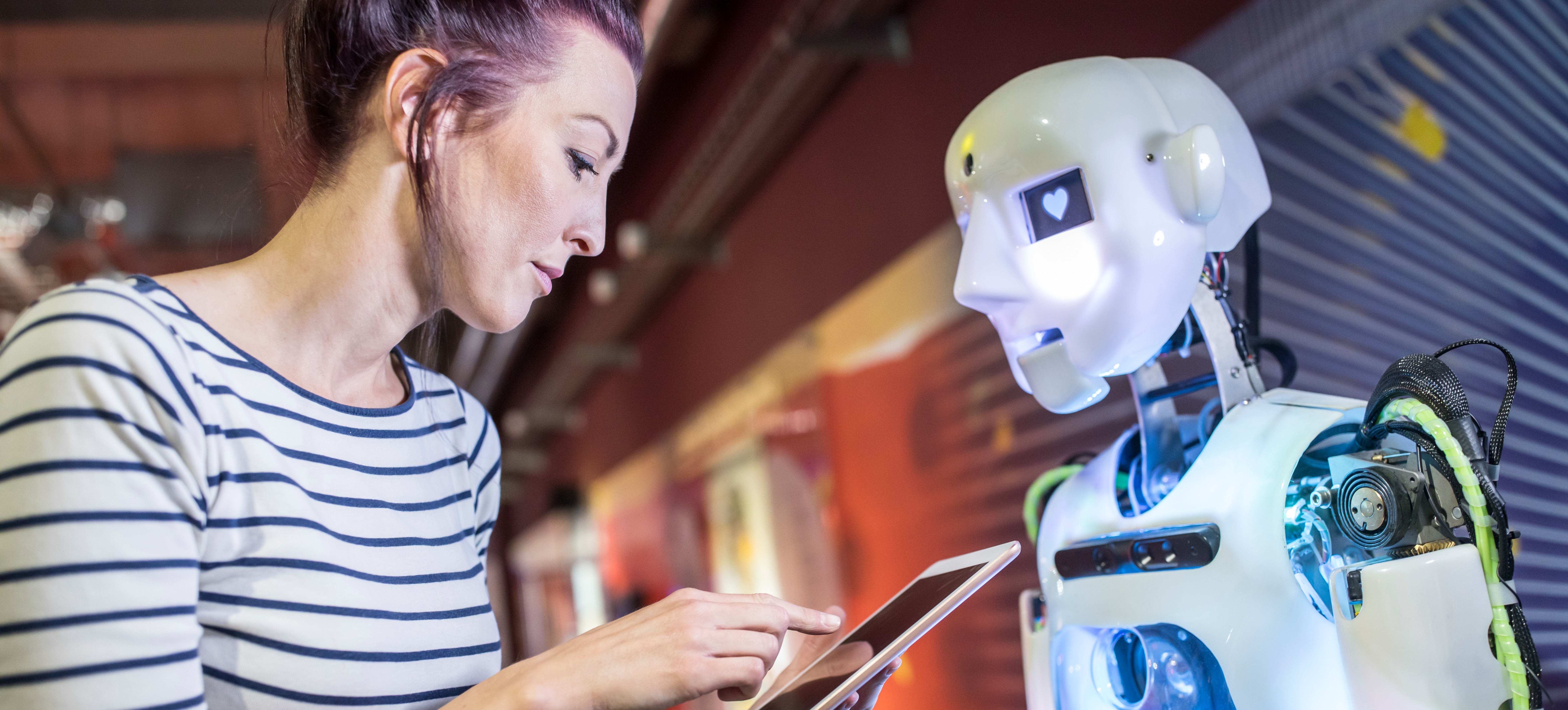 [Featured Image] A professional using a tablet to control an AI robot while being aware of their company's artificial intelligence policy.
