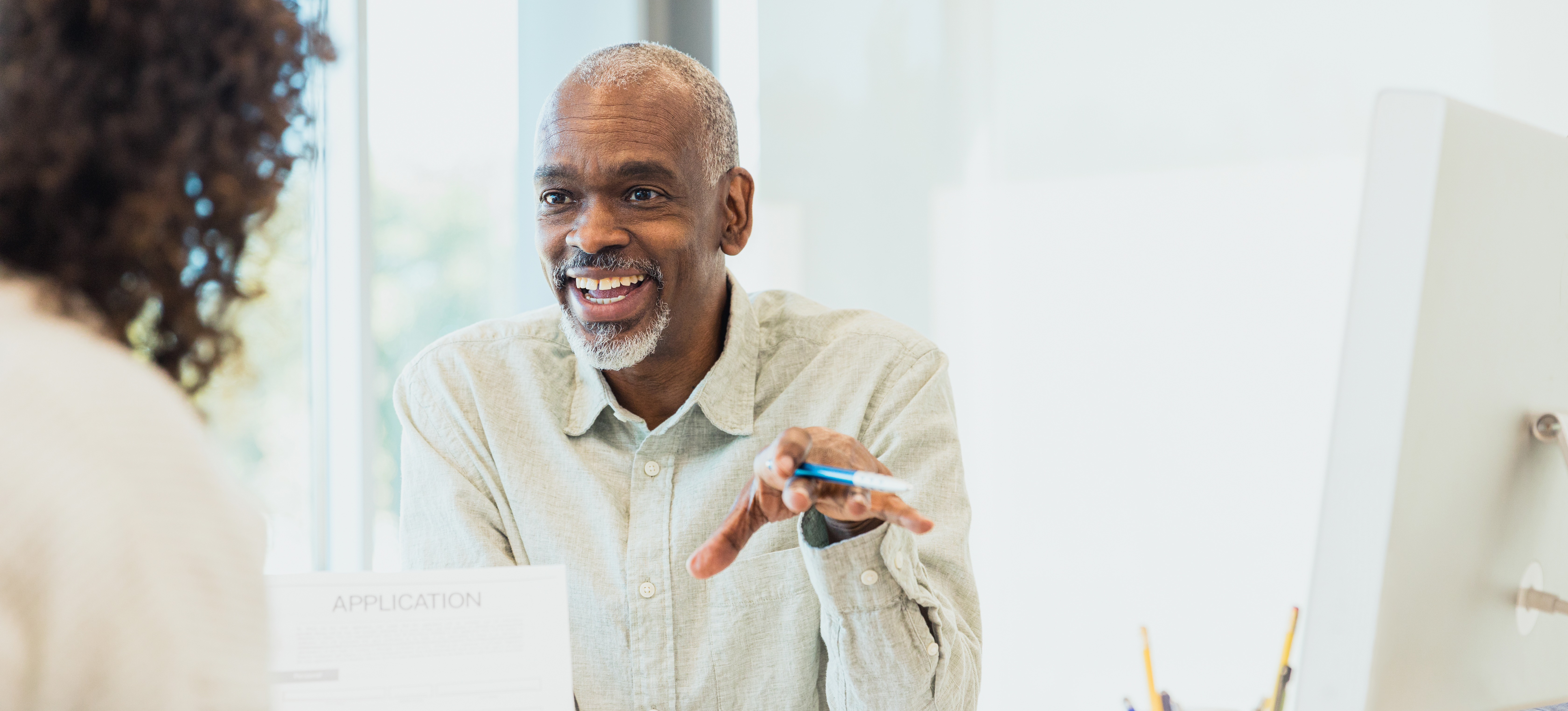 [Featured Image] A man working as an investment banker, one of the highest paying finance jobs, talks to his client across his desk.
