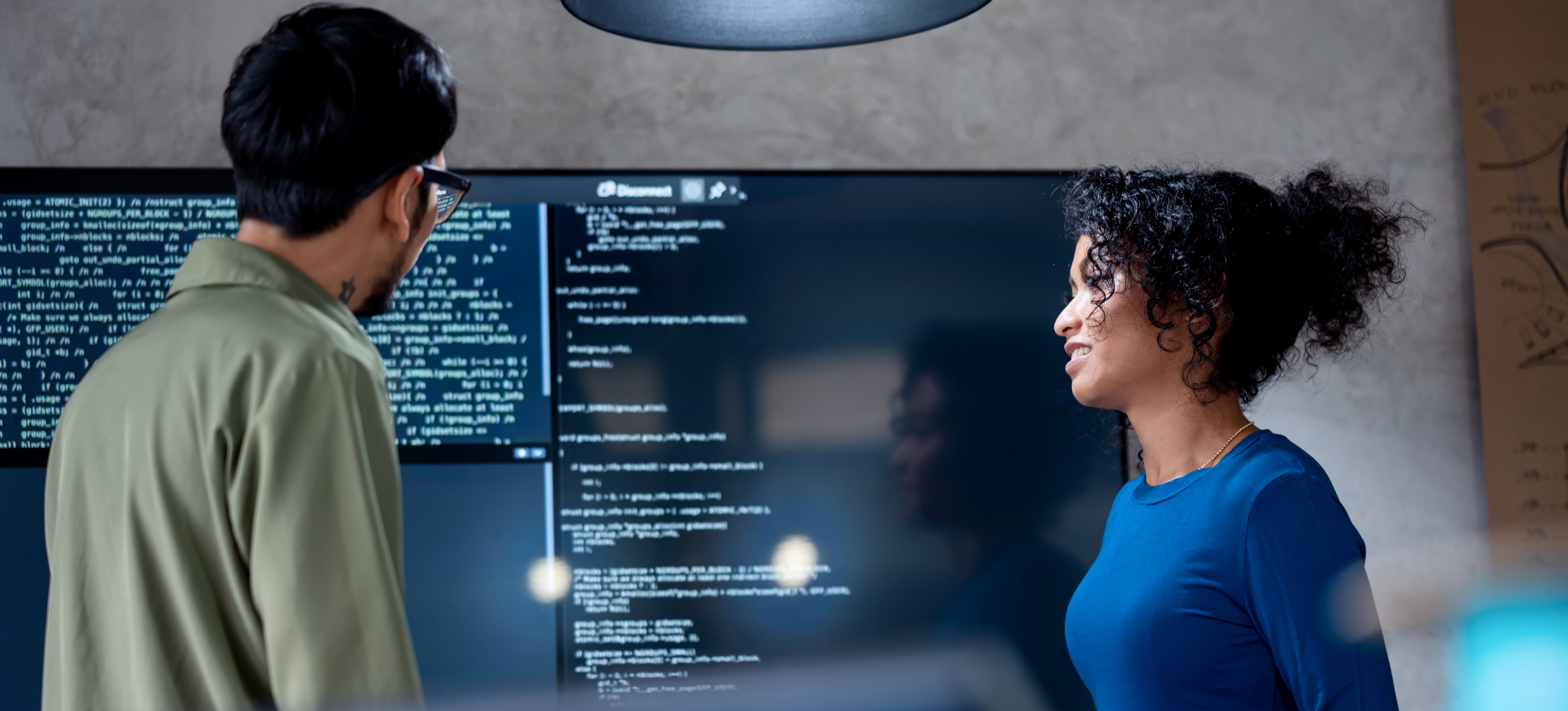 [Featured Image]: Two professionals with a master's in information technology review a computer system to ensure it operates properly.
