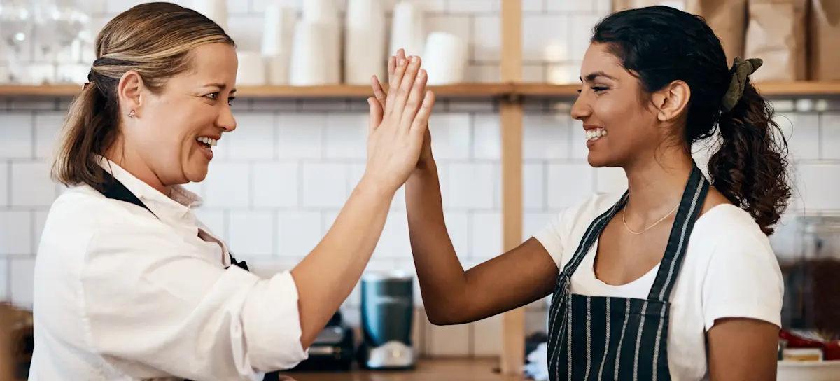 [Featured Image] After finding one of five types of part-time jobs for college students, a new barista high-fives their mentor who trained them. 
