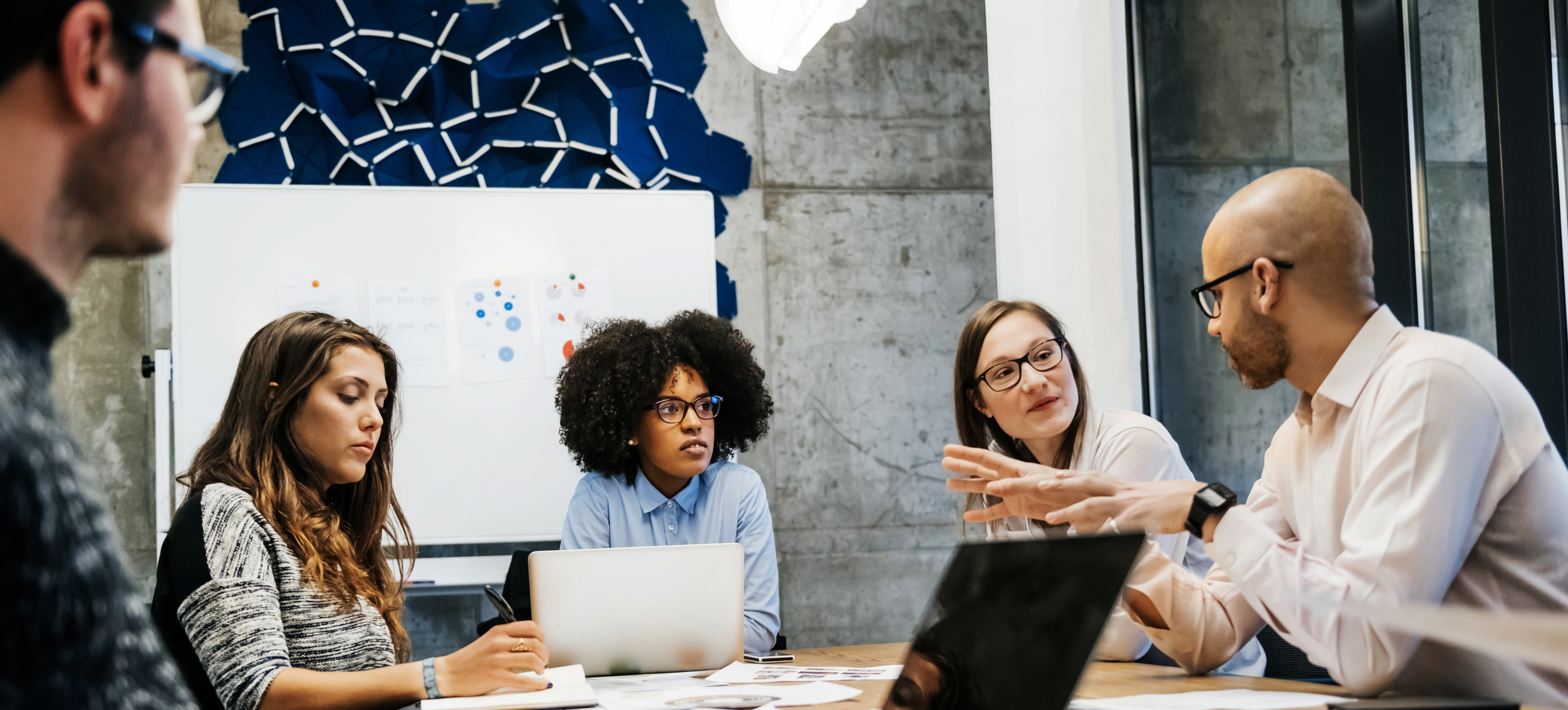 [Featured Image] A technology team in a professional meeting room discussing Angular vs. React.

