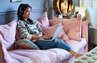 [Featured image] A software developer is wearing headphones and working on her laptop from home.