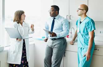 [Featured image] A health care consultant speaks with doctors inside a hospital room.