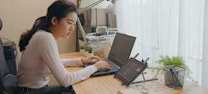 [Featured image] A person in a white long-sleeved shirt sits at a desk investigating a Python syntax error in thier code on a laptop and tablet.