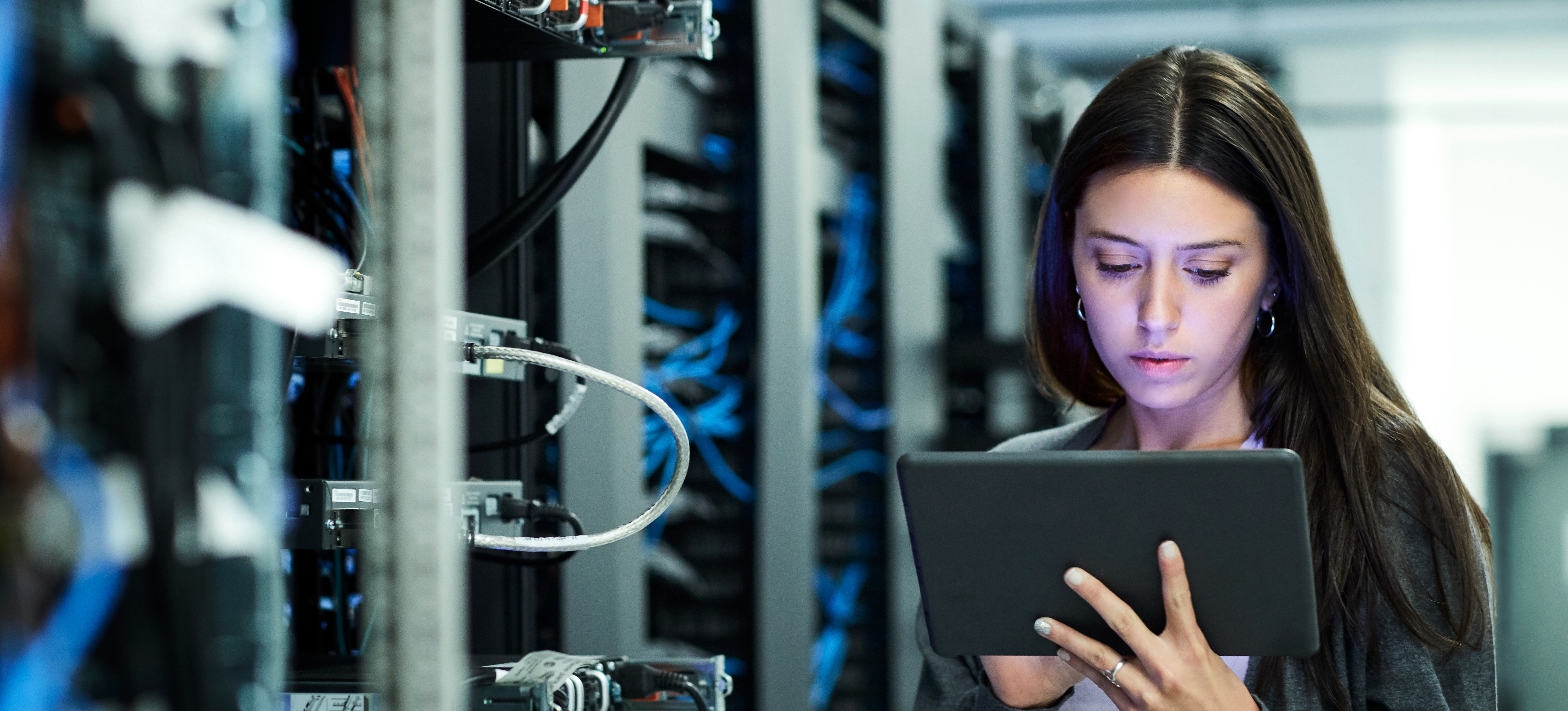 [Featured Image], An engineer refers to their network engineer certifications while working in a company’s server room.