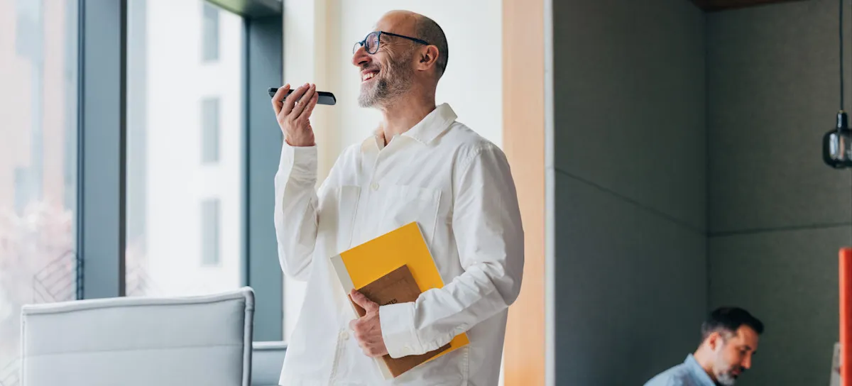 [Featured image]: A person smiles as they speaks into a cell phone using ChatGPT Voice Mode.
