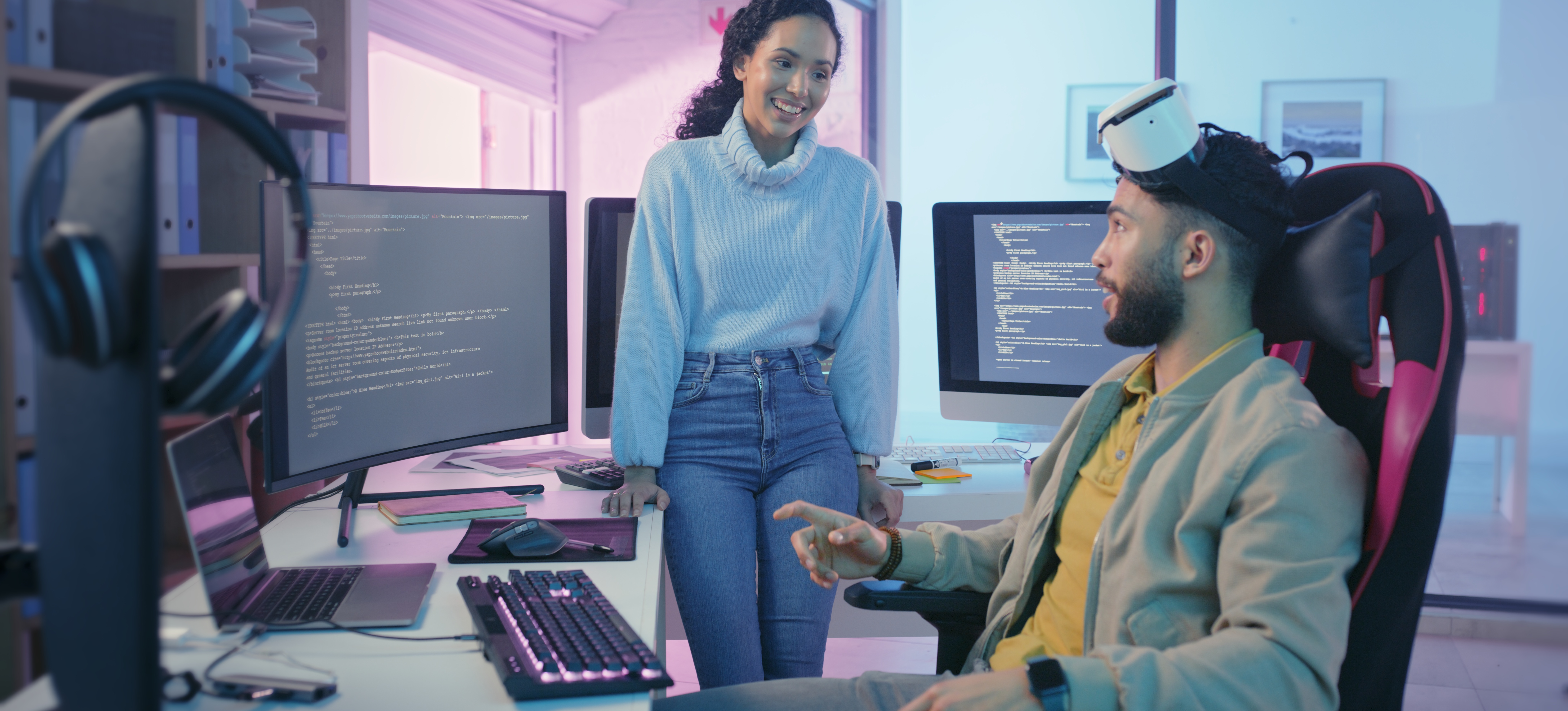 [Featured Image] Game development specialists in a workspace interact while reviewing C++ code on a computer screen, discussing how long it takes to learn C++ for games.